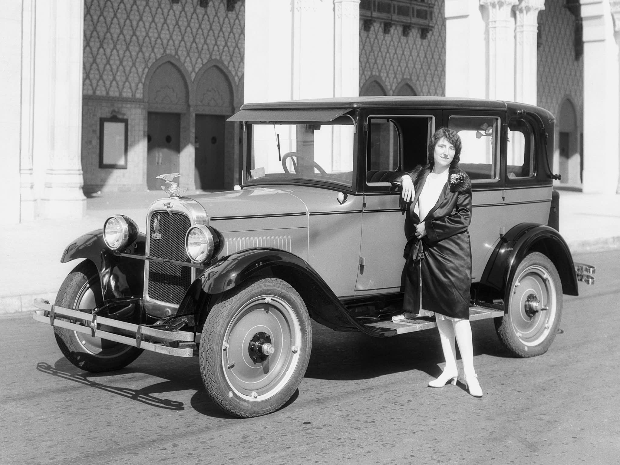 A woman standing next to a 1927 Chevrolet Capitol