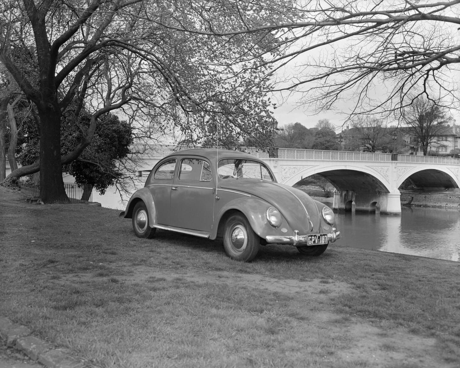 A 1956 Volkswagen Beetle parked on the embankment of a waterway