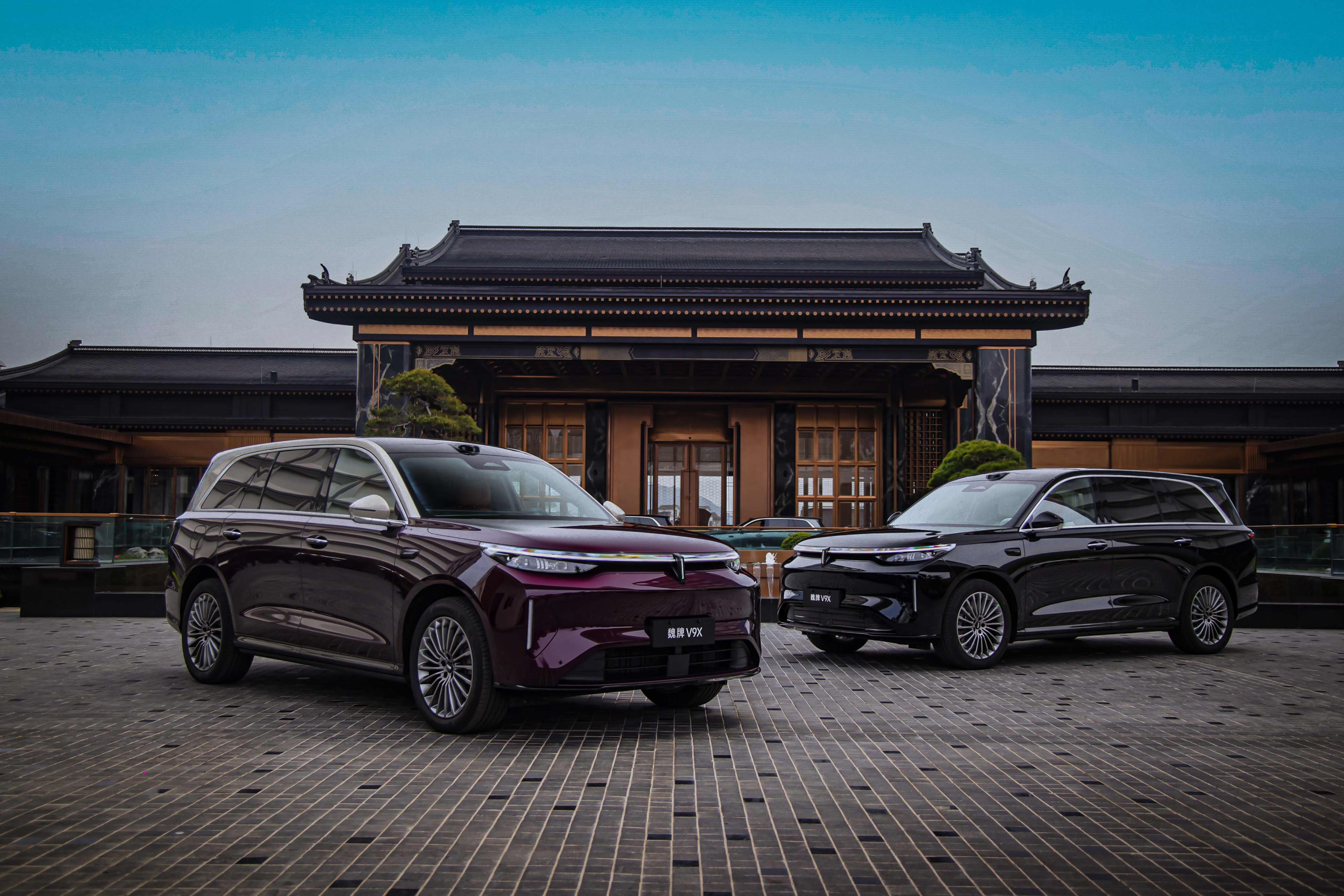 Two GWM Wey V9X cars in front of a temple