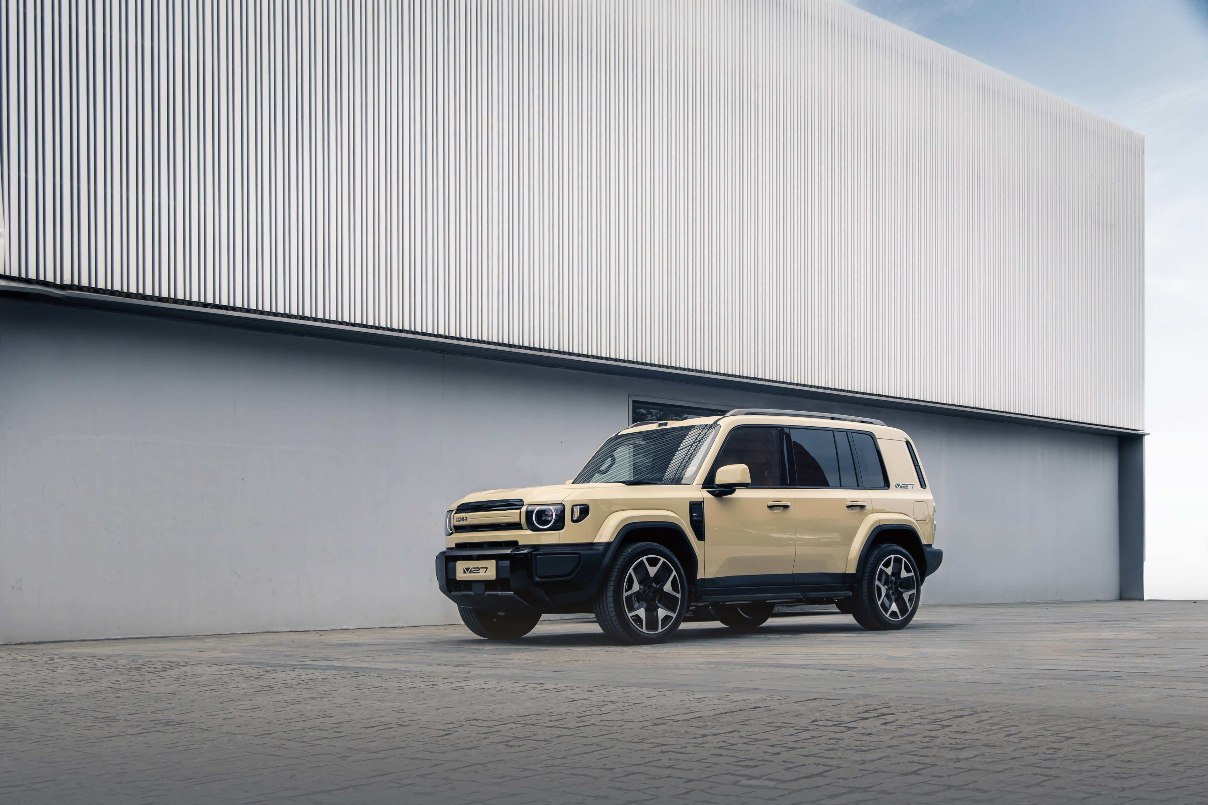 A beige iCaur in front of a warehouse