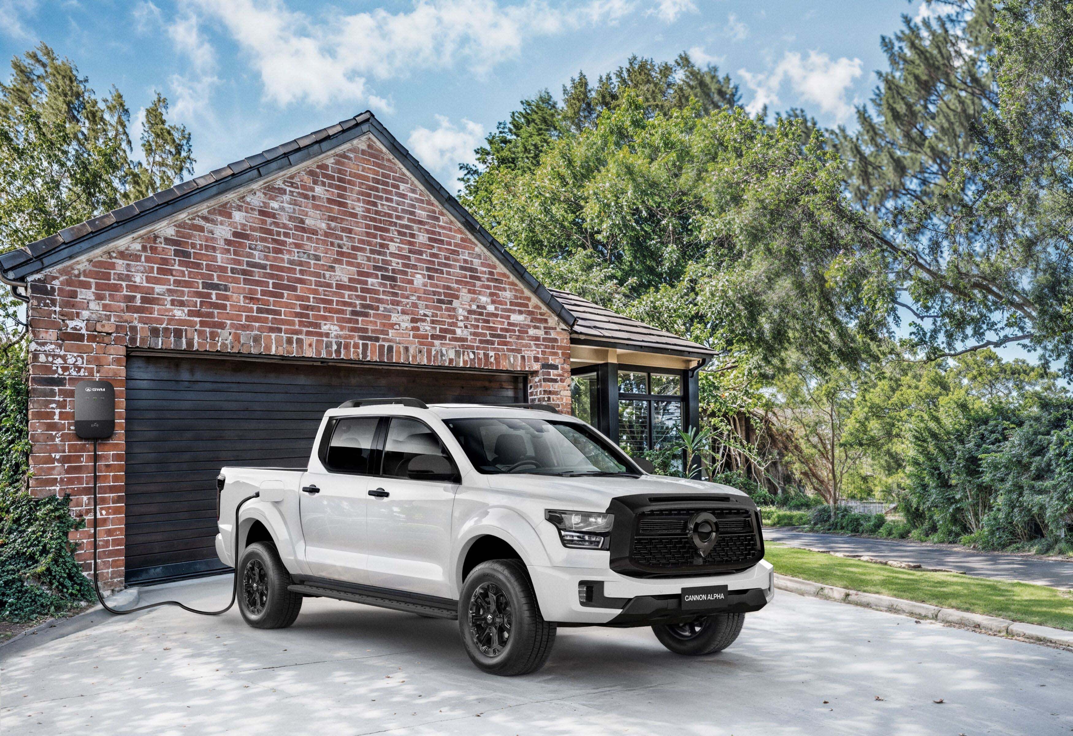 A white GWM Cannon Alpha PHEV ute being charged in a suburban driveway