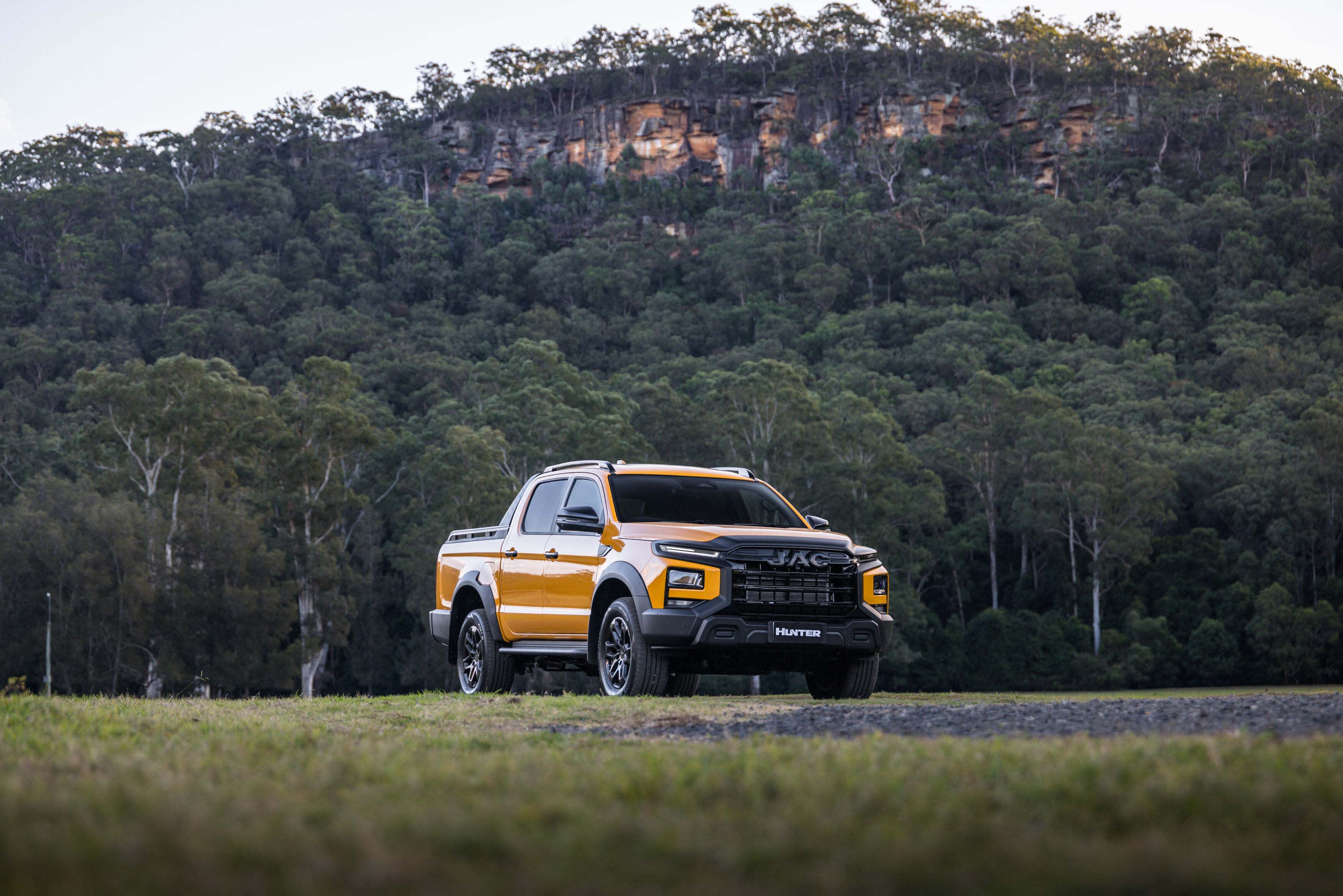 A JAC Hunter PHEV dual cab ute in a paddock near a hillside