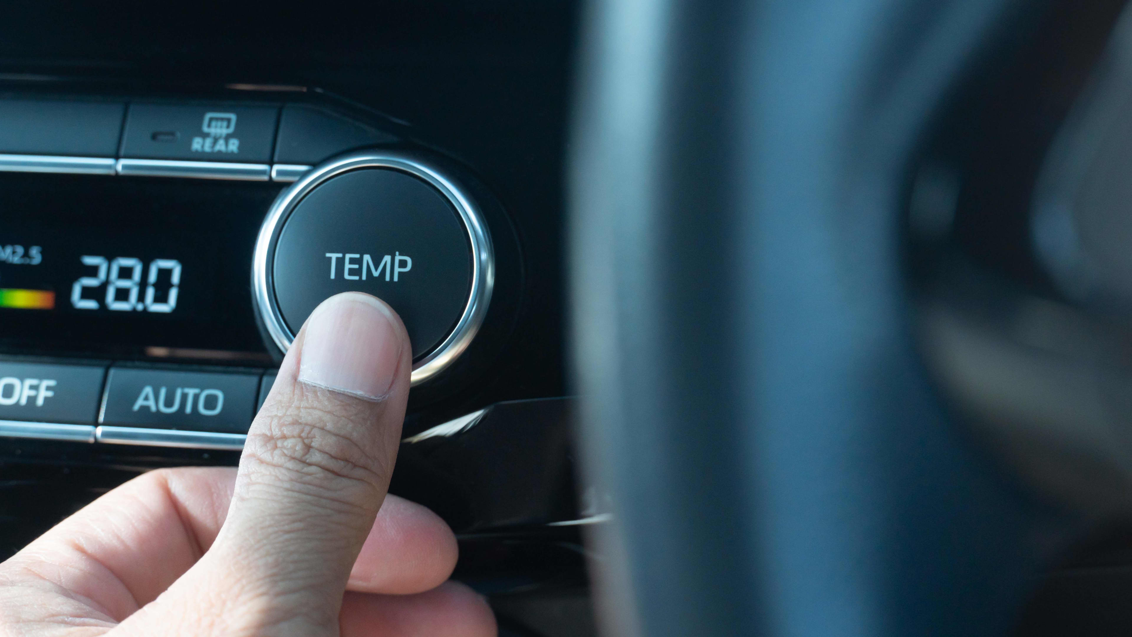 A person pressing a button on a car console