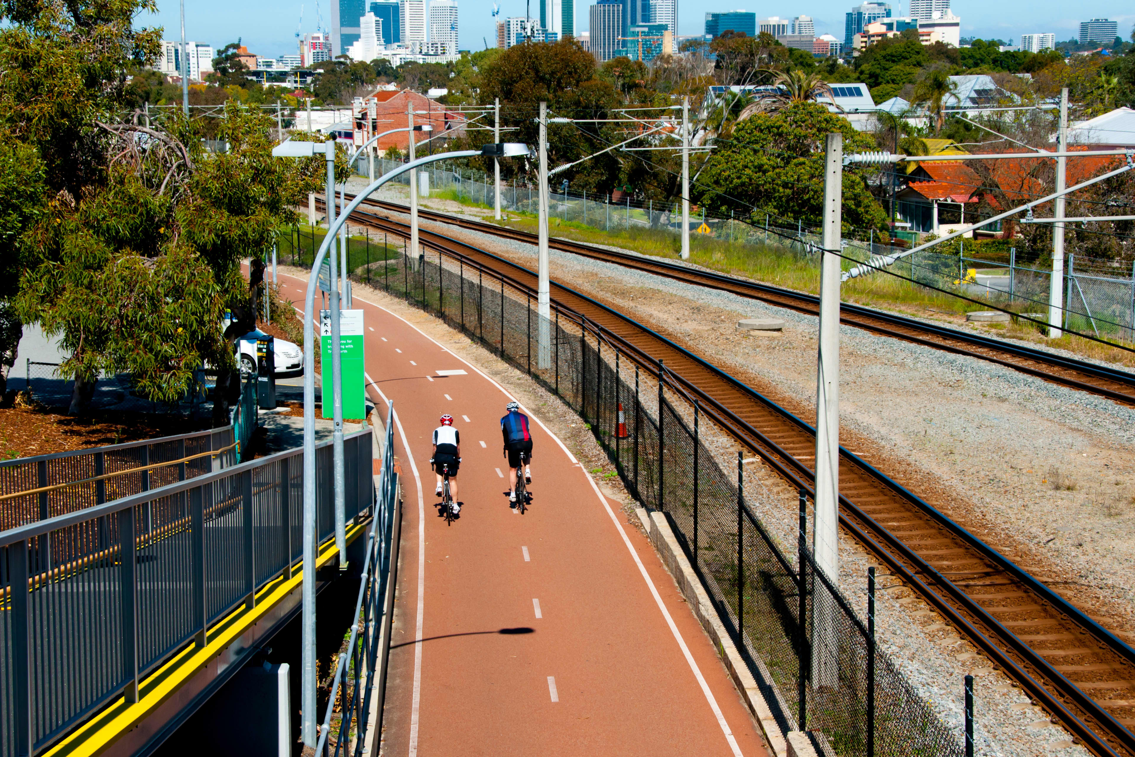 Two cyclists riding along a freeway bike lane in Perth