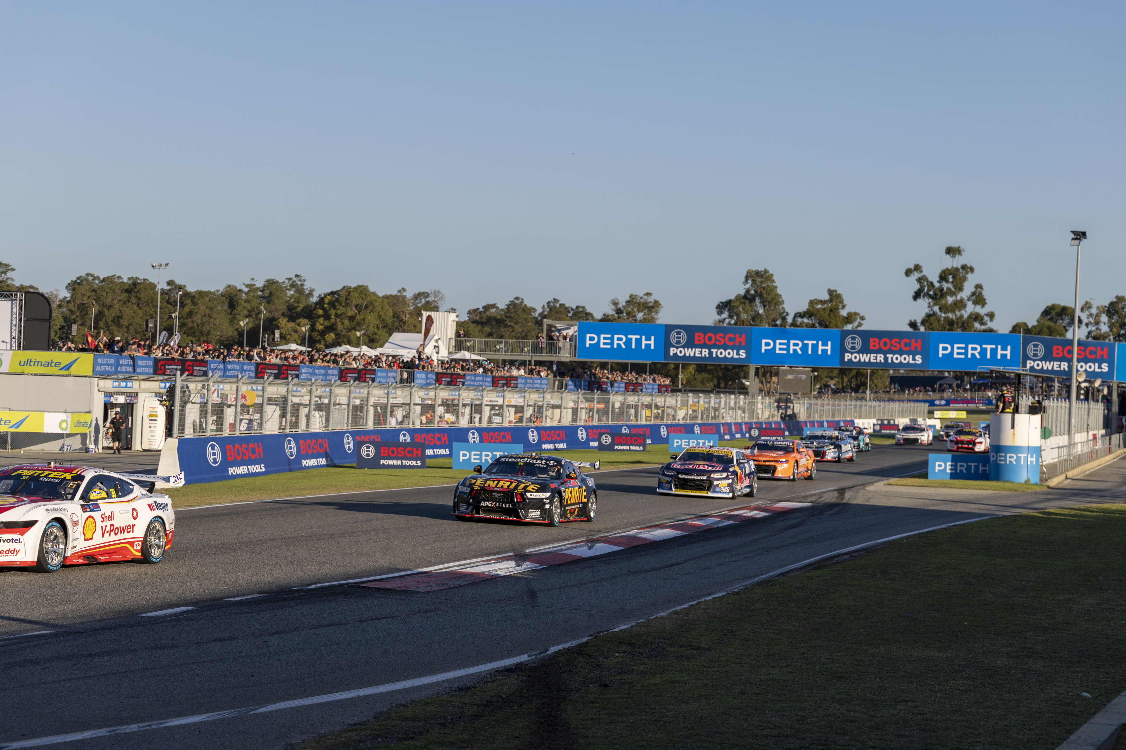 Supercars on race track with fans watching in background