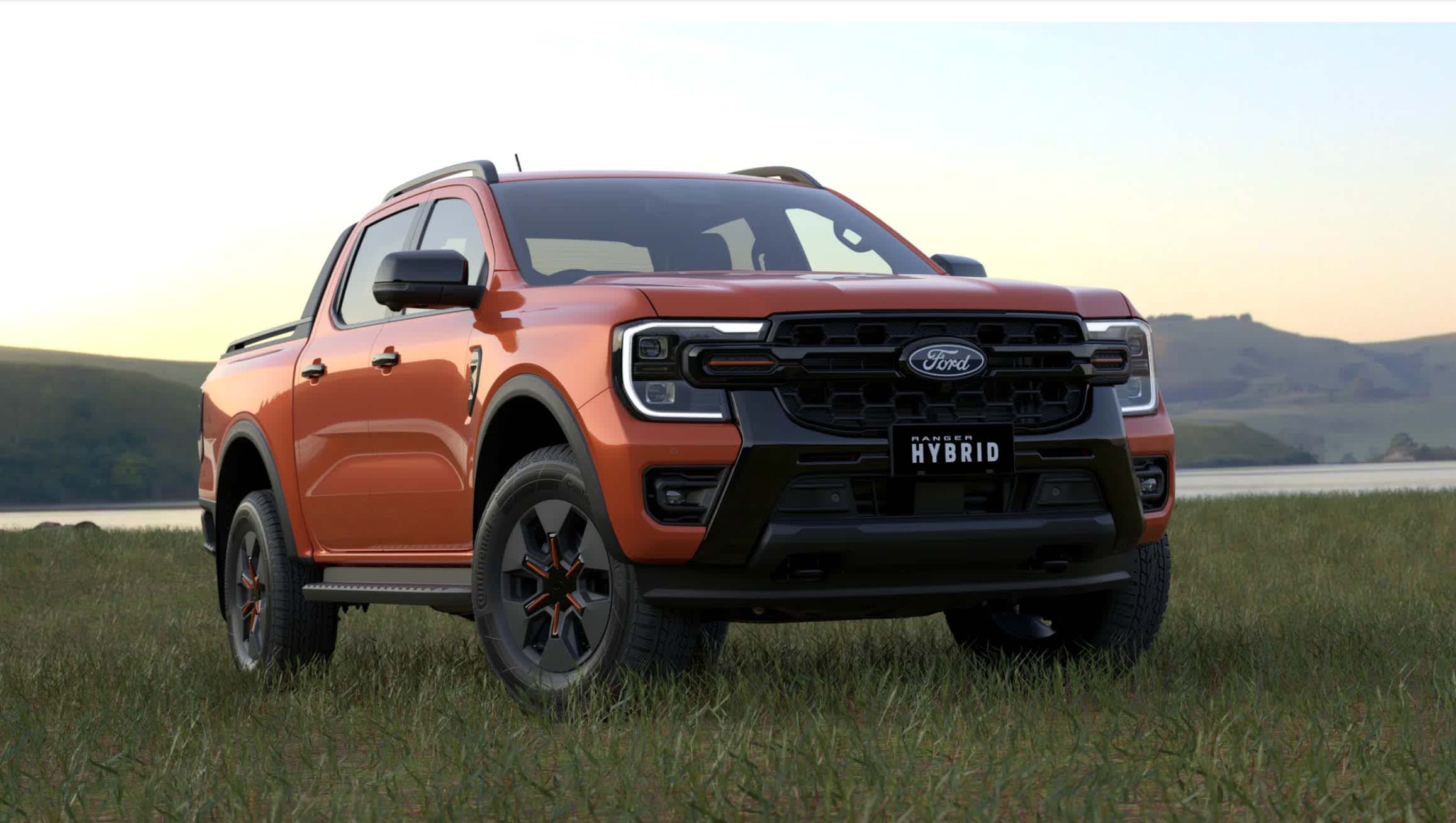 An orange Ford Ranger PHEV ute parked on a grass near a lake