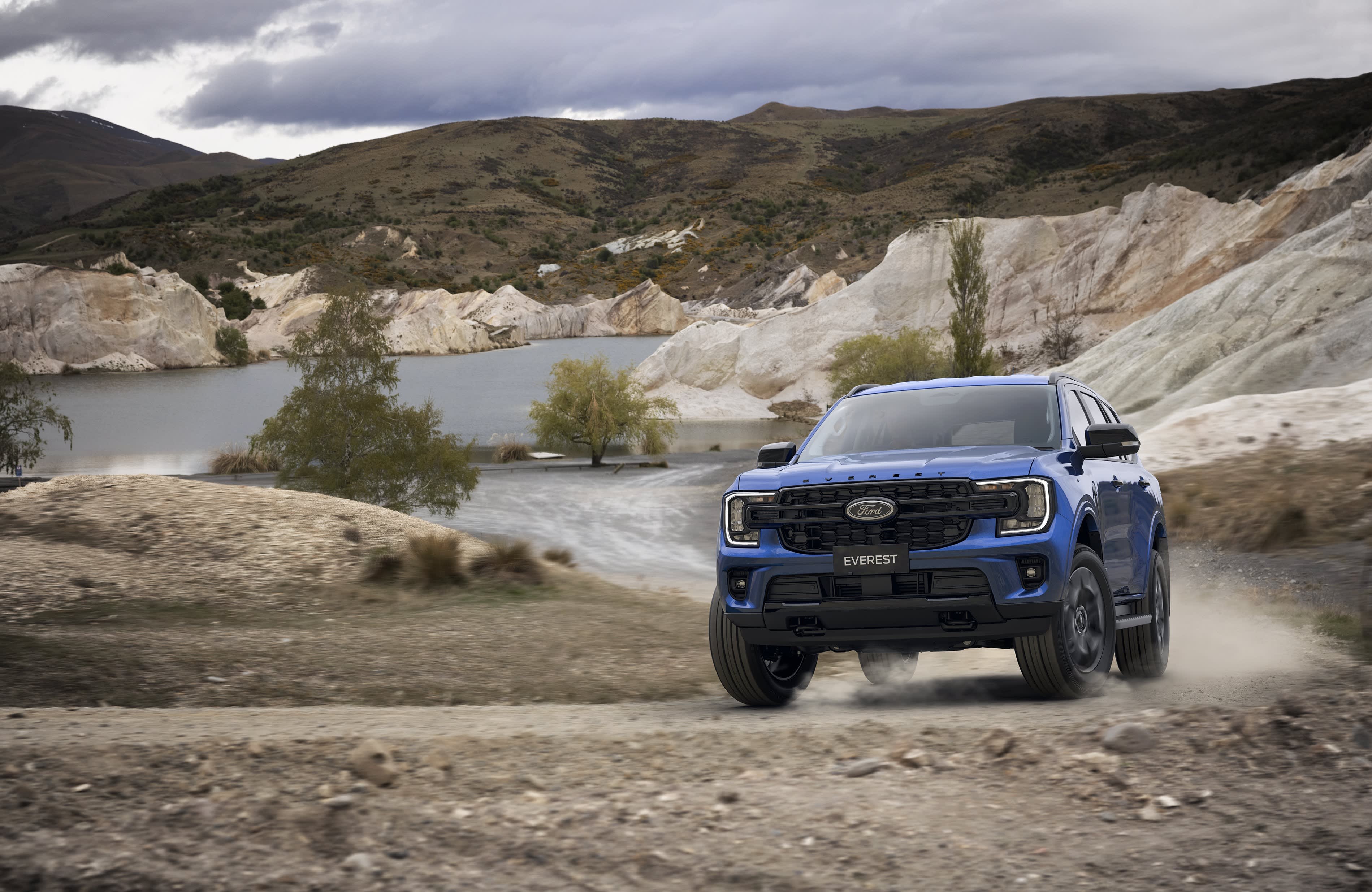 A dark blue Ford Everest driving up a hill on a dusty dirt track