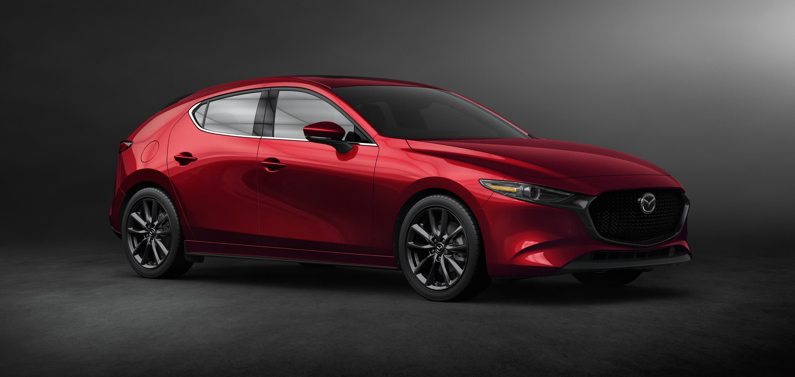 A red Mazda3 hatch in a dark studio setting