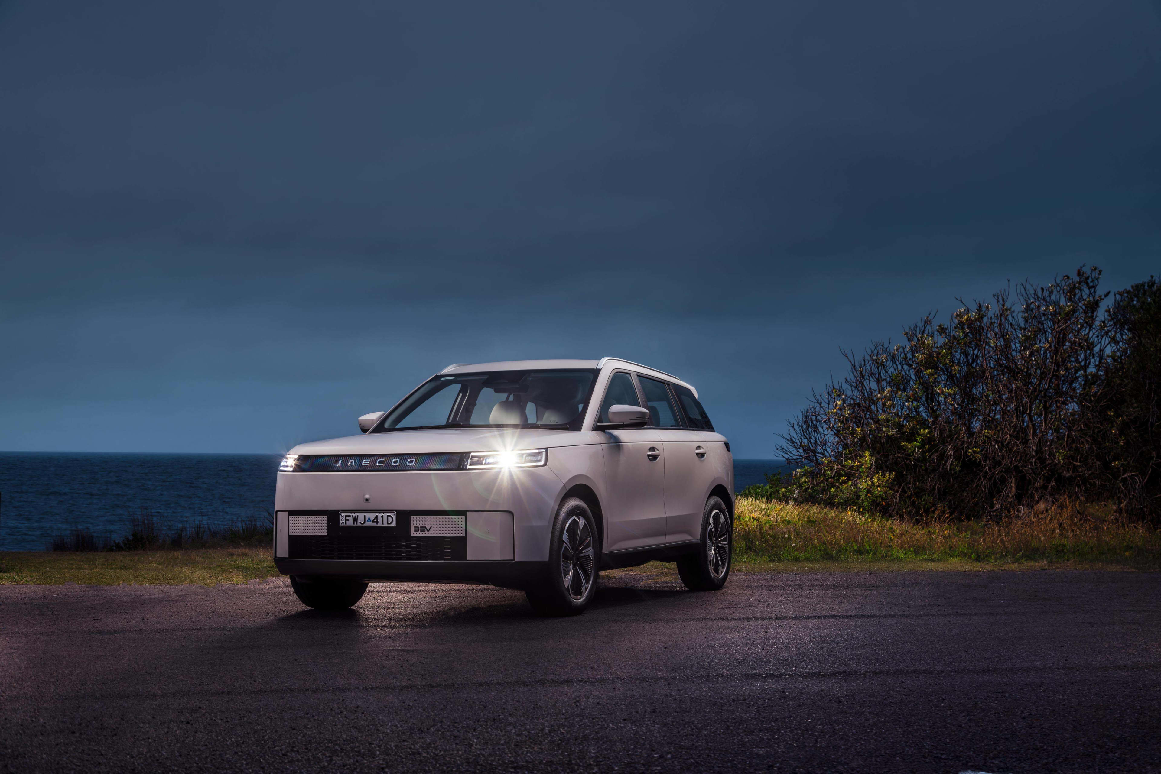 A white Jaecoo J5 EV parked on a tarmac in the countryside at night