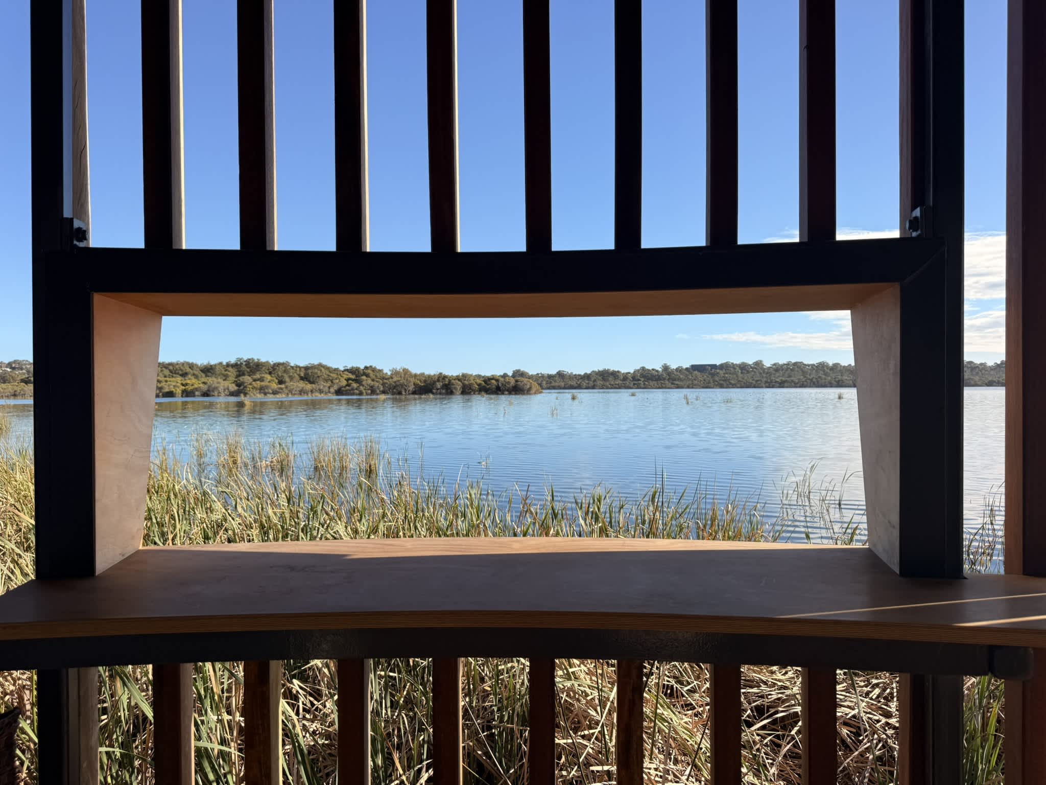 Timber window opening of tower overlooking reeds and lake.