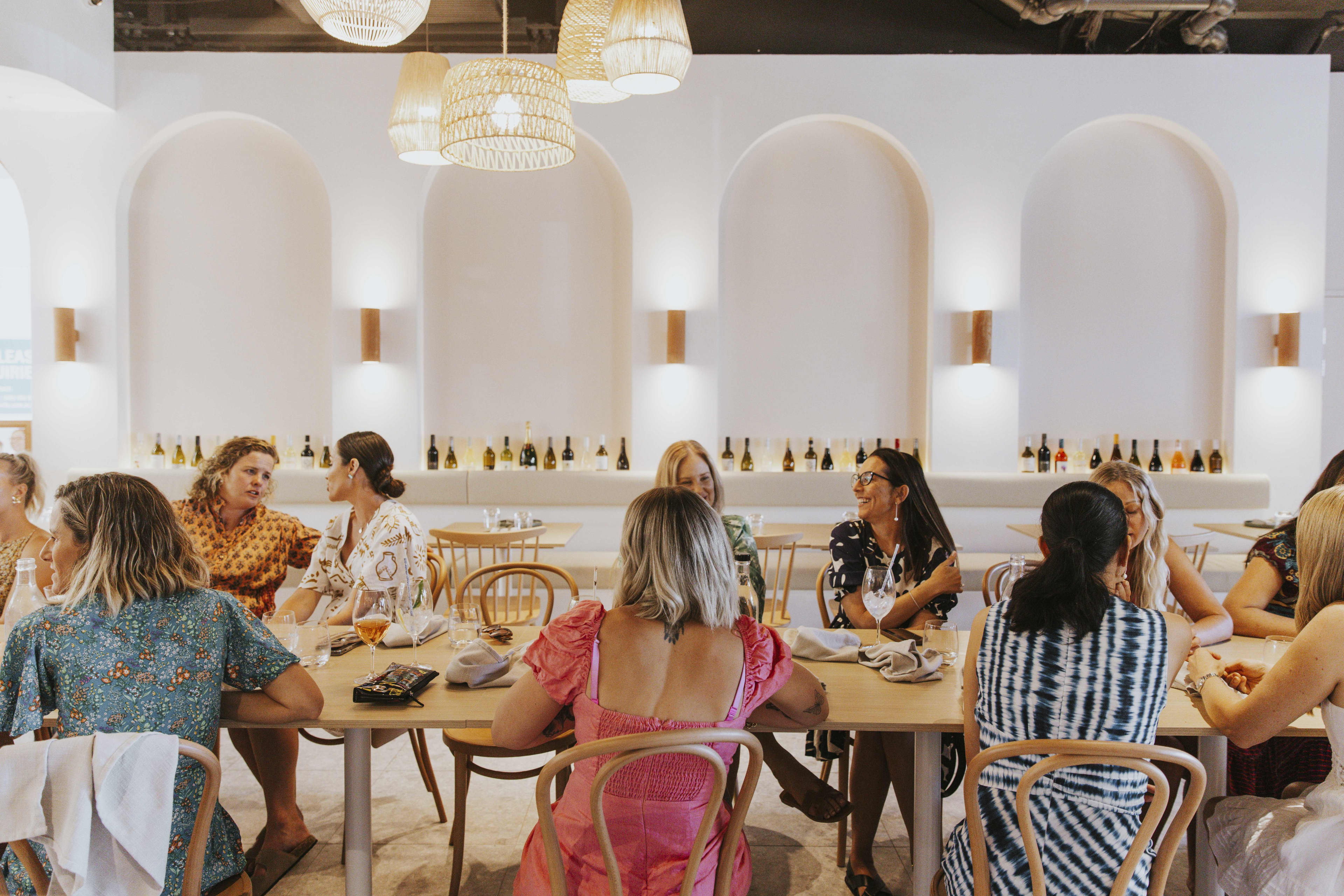 Group of people sitting around long table in light-filled restaurant.