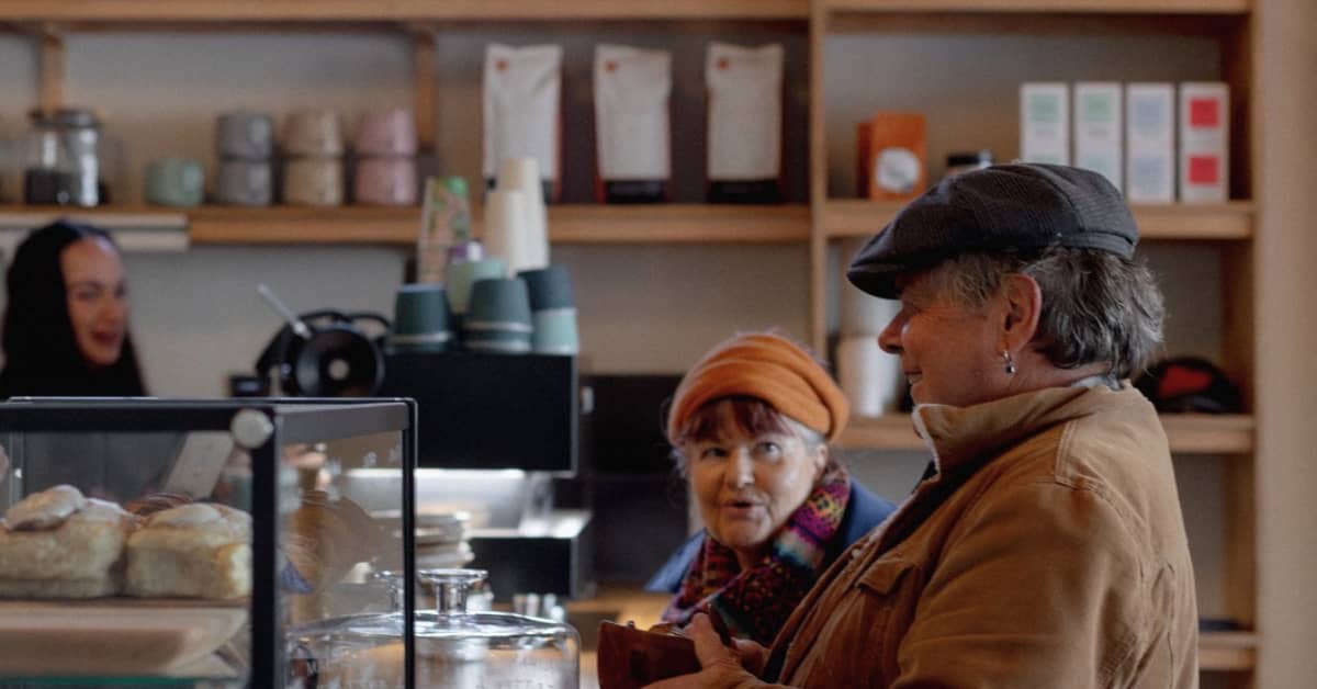 Two people ordering coffee at counter of cafe