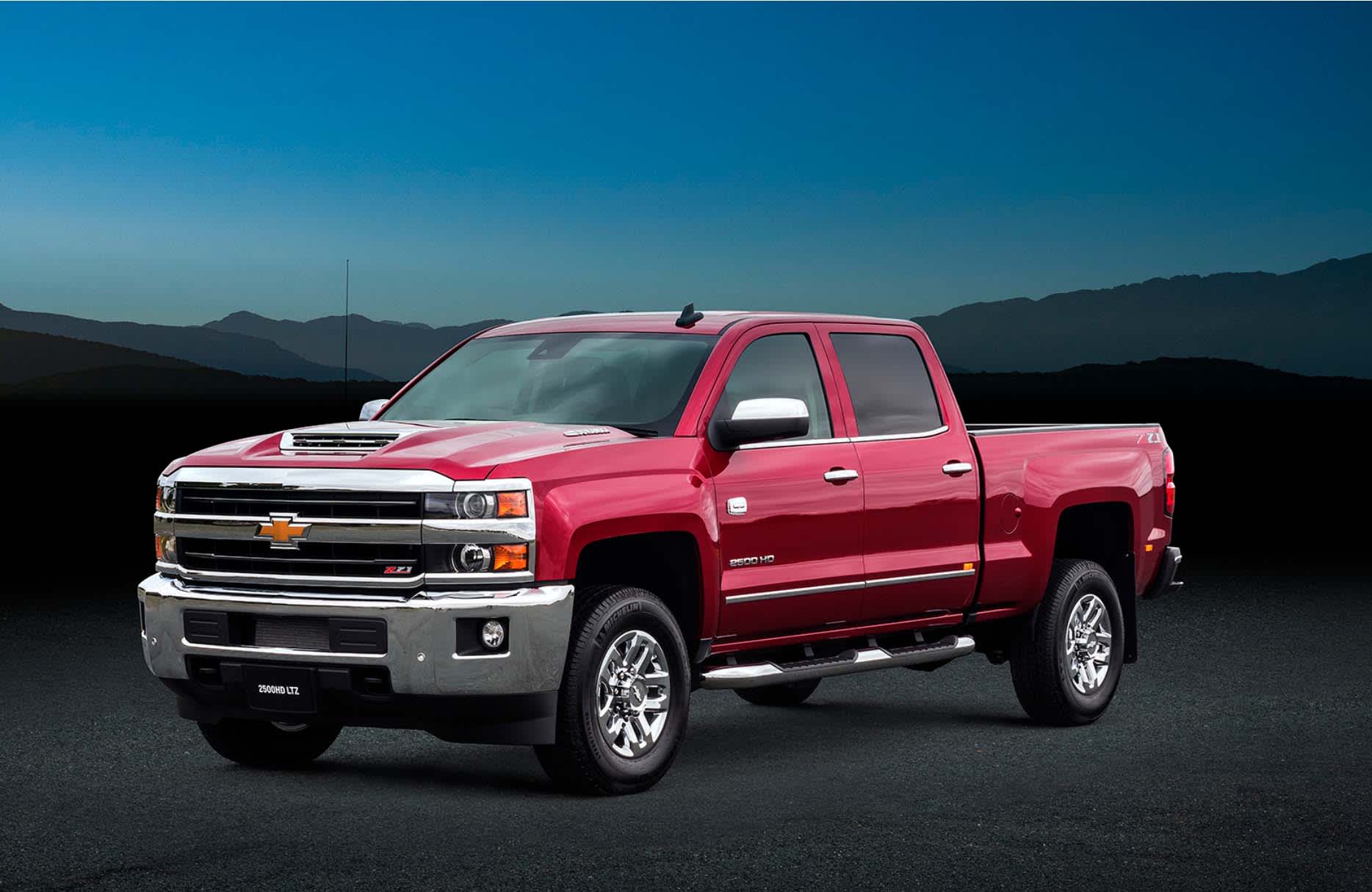 A red Chevrolet Silverado parked near mountains after sunset