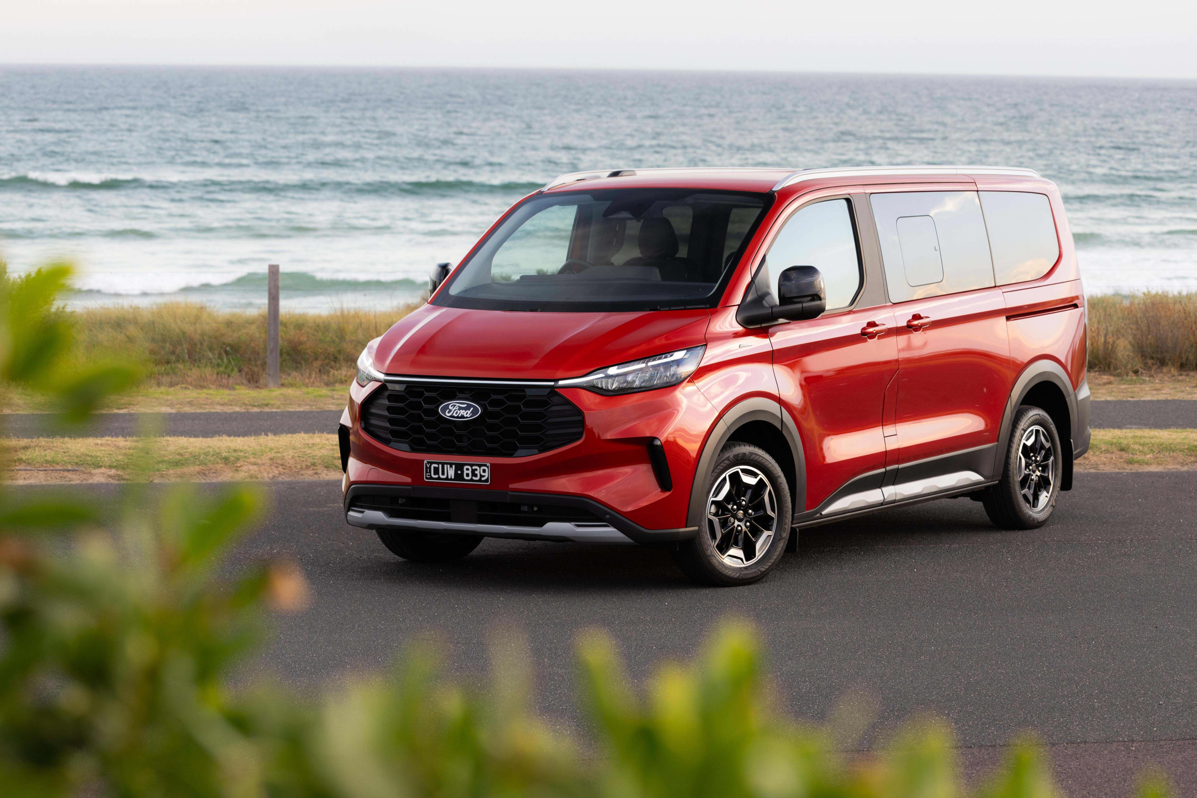 A red Ford Tourneo Custom van parked near a beach