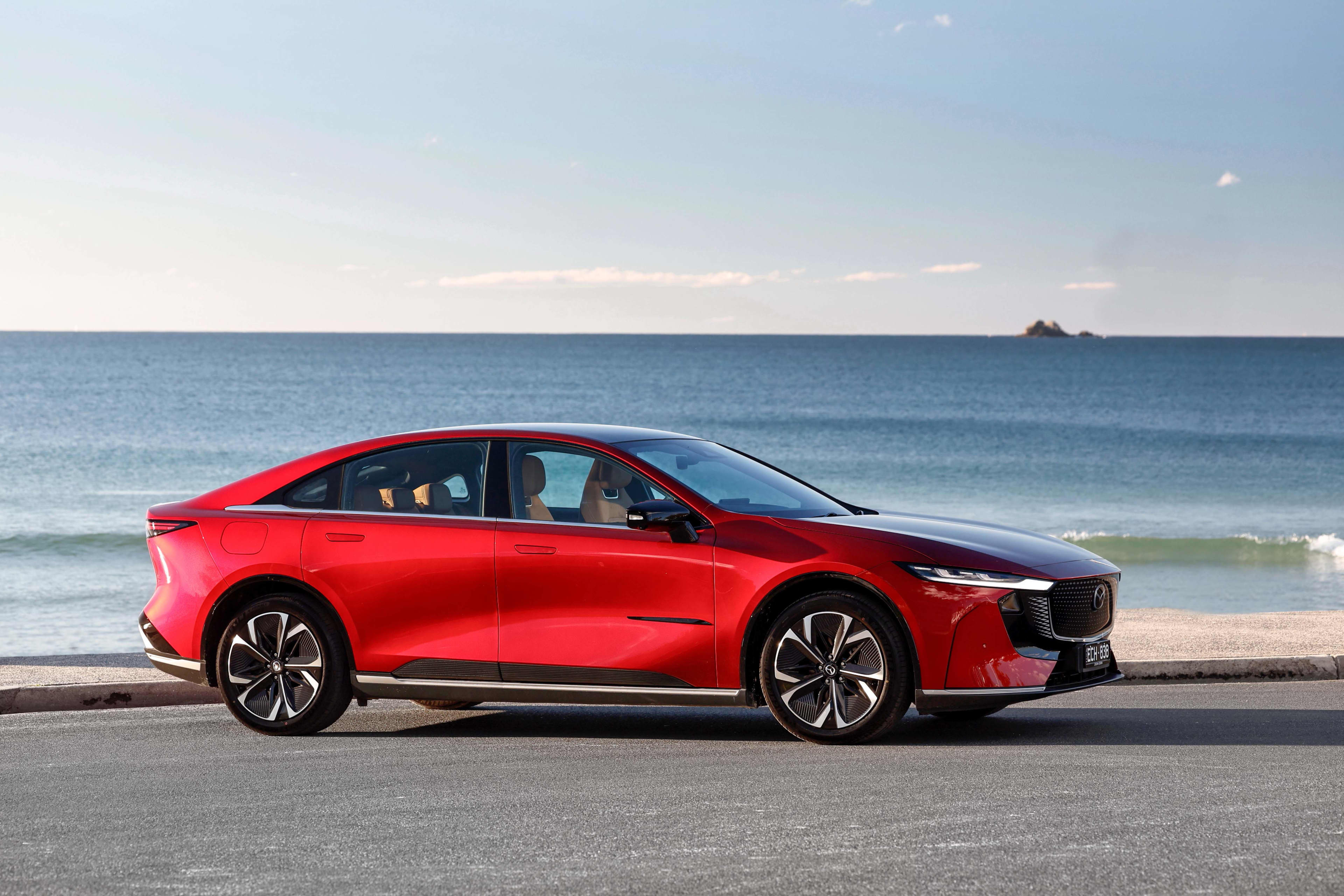 A red Mazda 6e GT parked near a beach