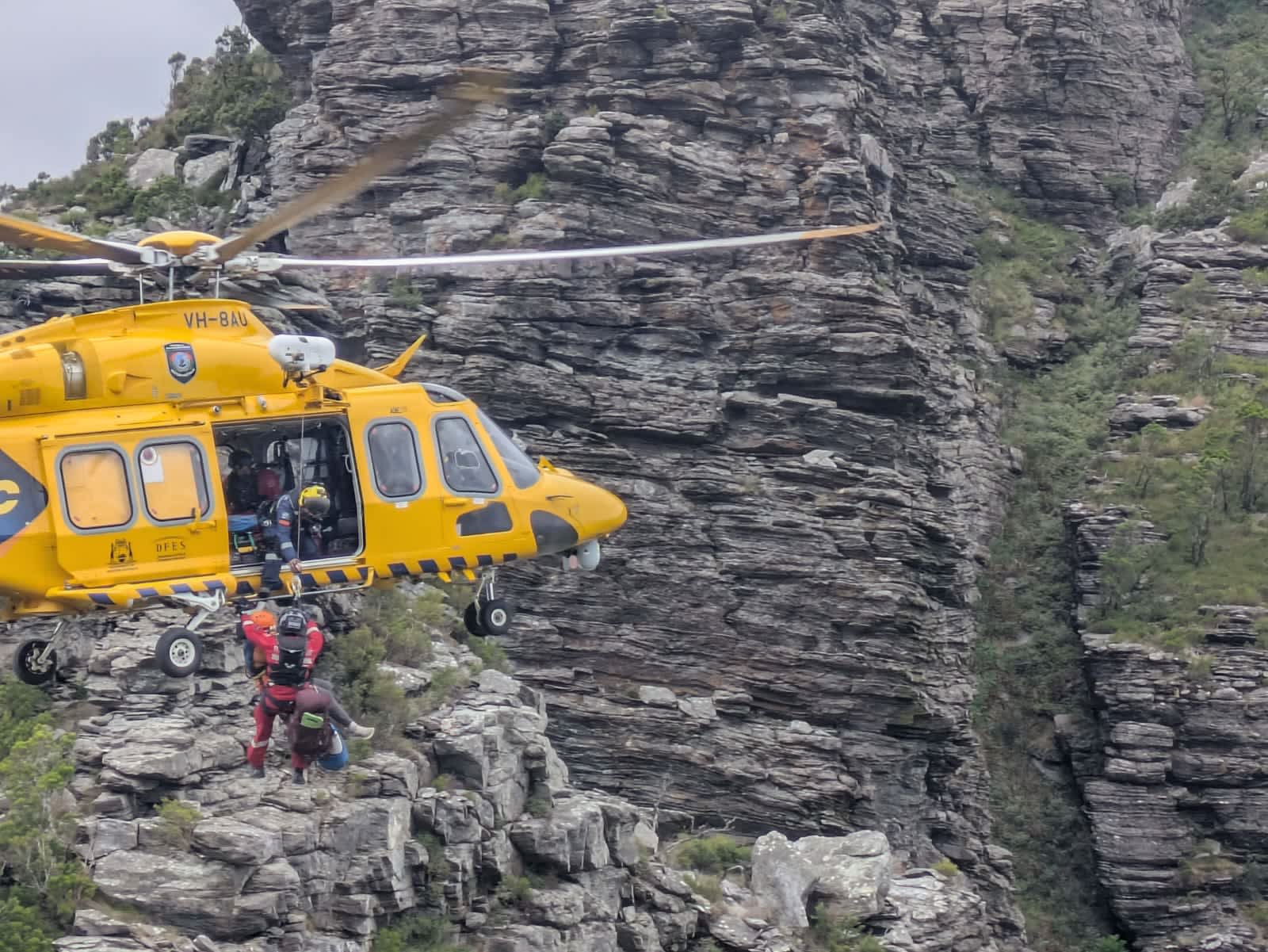 RAC rescue helicopter in front of Bluff Knoll, winching up patient.