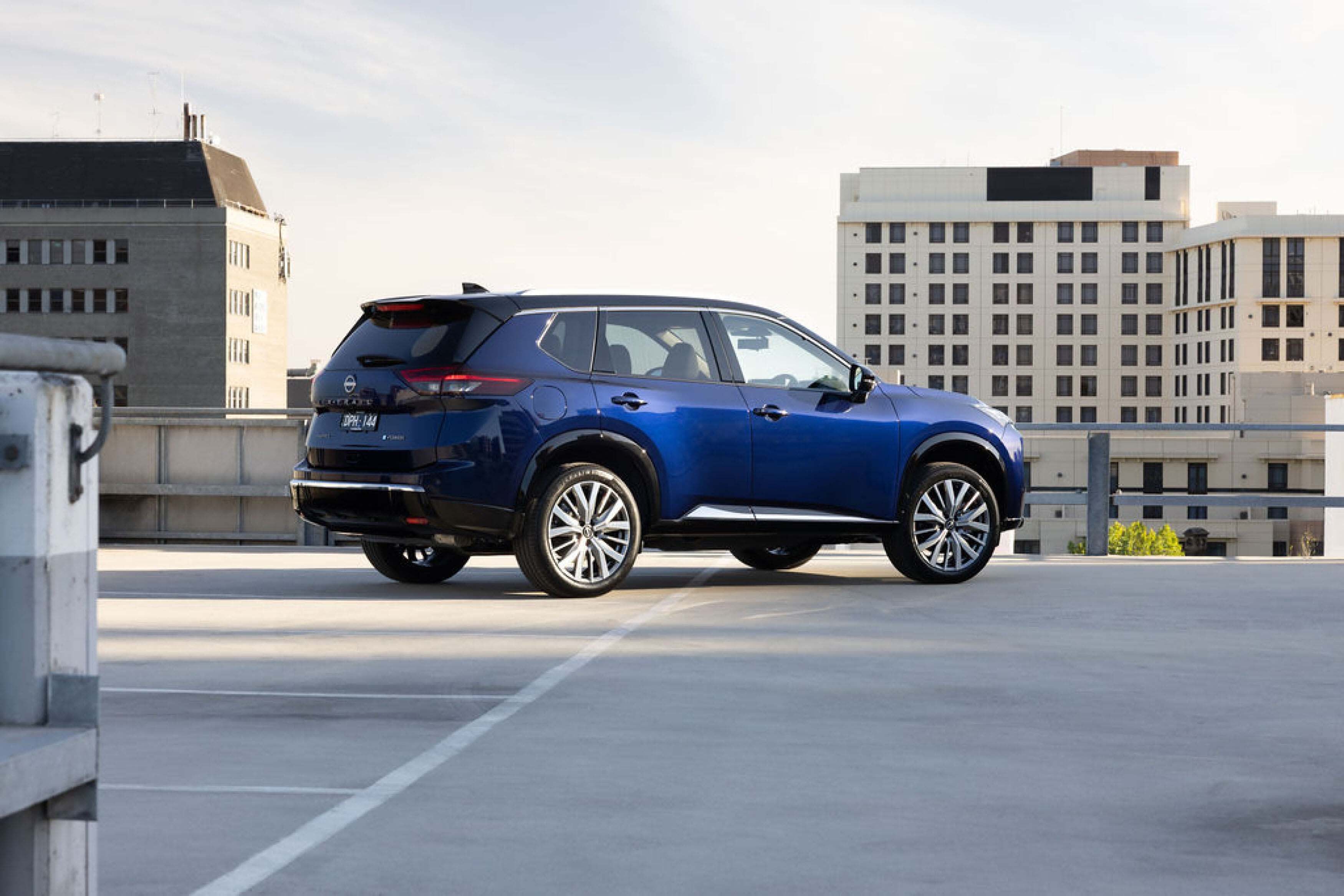 A blue Nissan X-TRAIL Ti-L parked on the roof of a city building