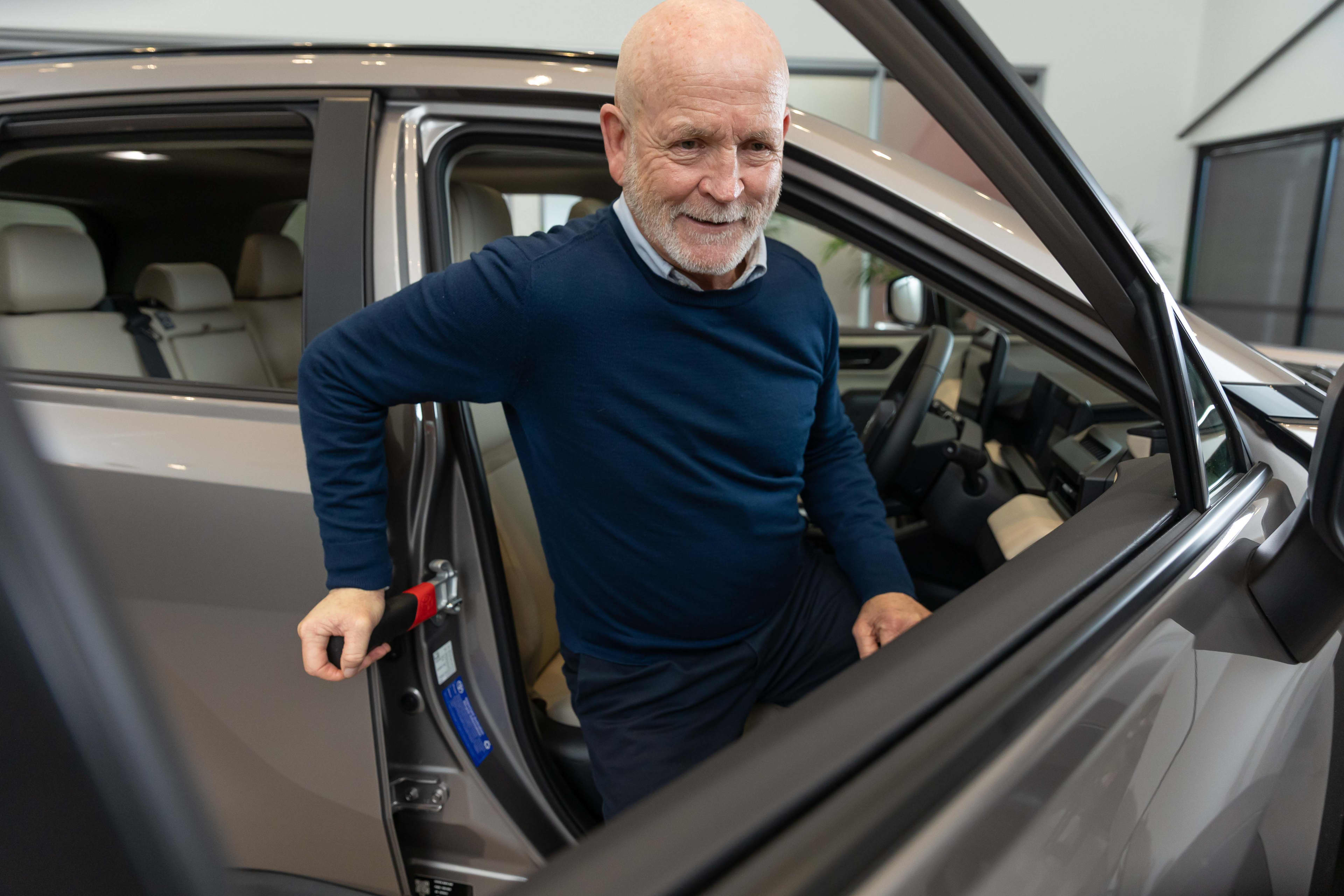 A man exiting a car using a mobility grip