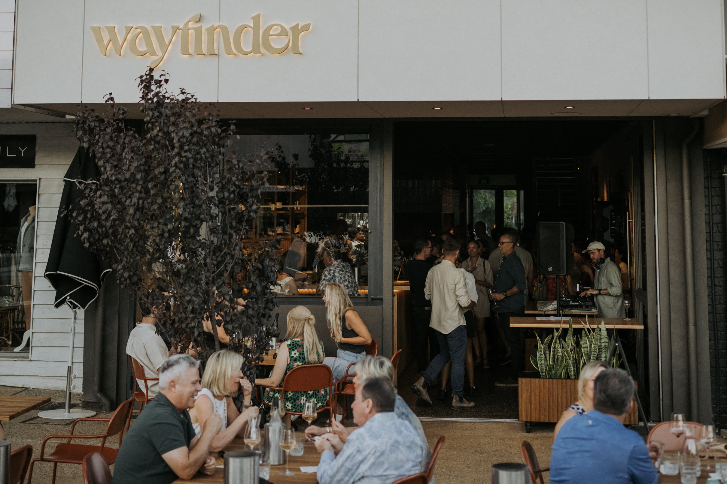 People seated at outdoor tables at Wayfinder restaurant