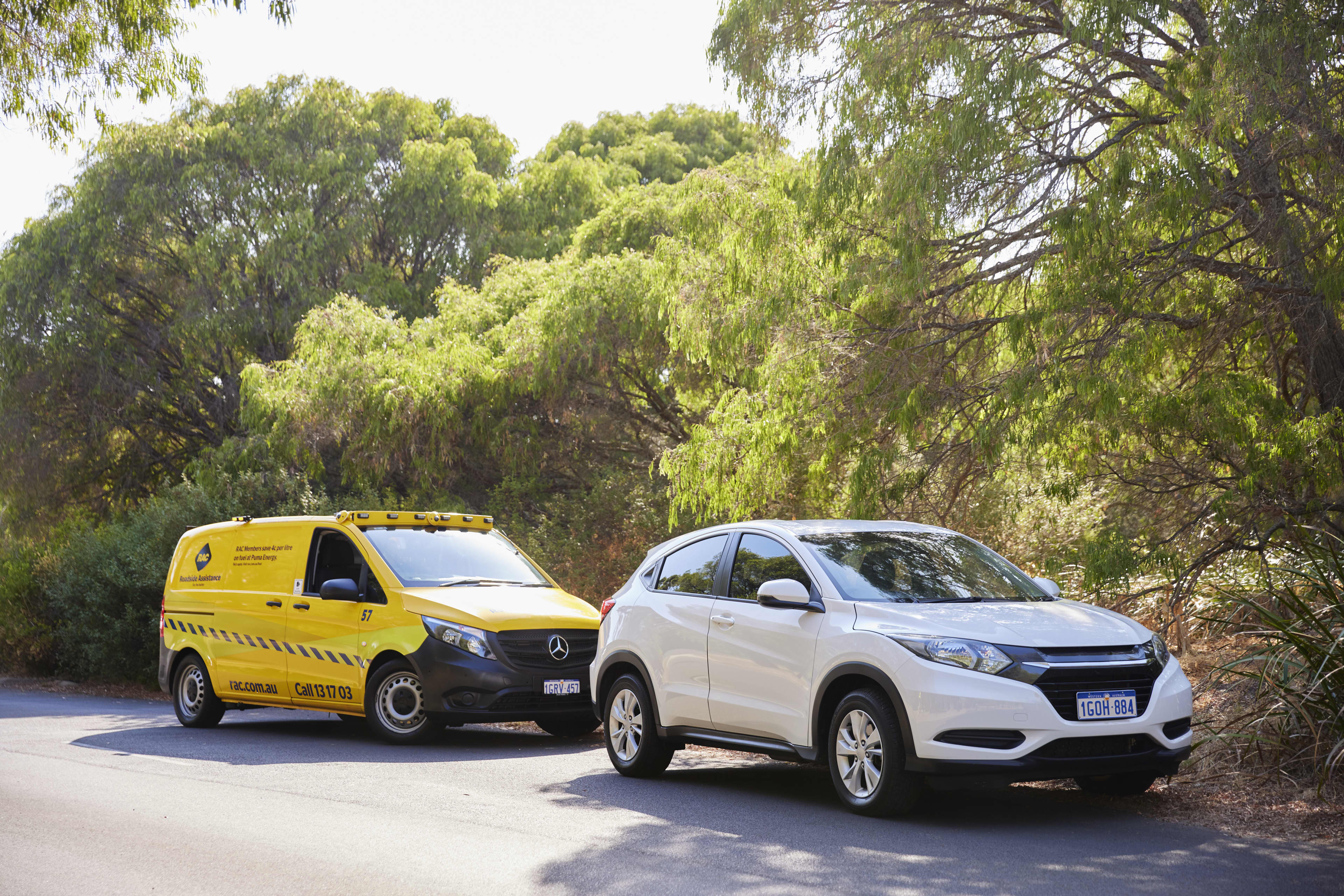 Yellow RAC Roadside van parked behind broken down car on rural road.