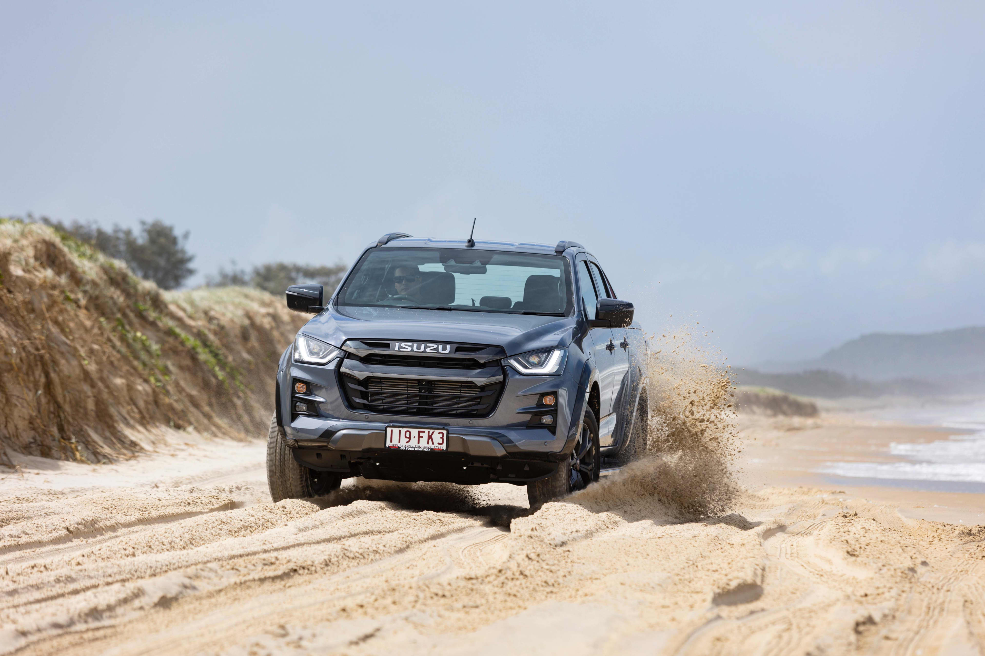 A silver Isuzu D-Max driving on the beach.