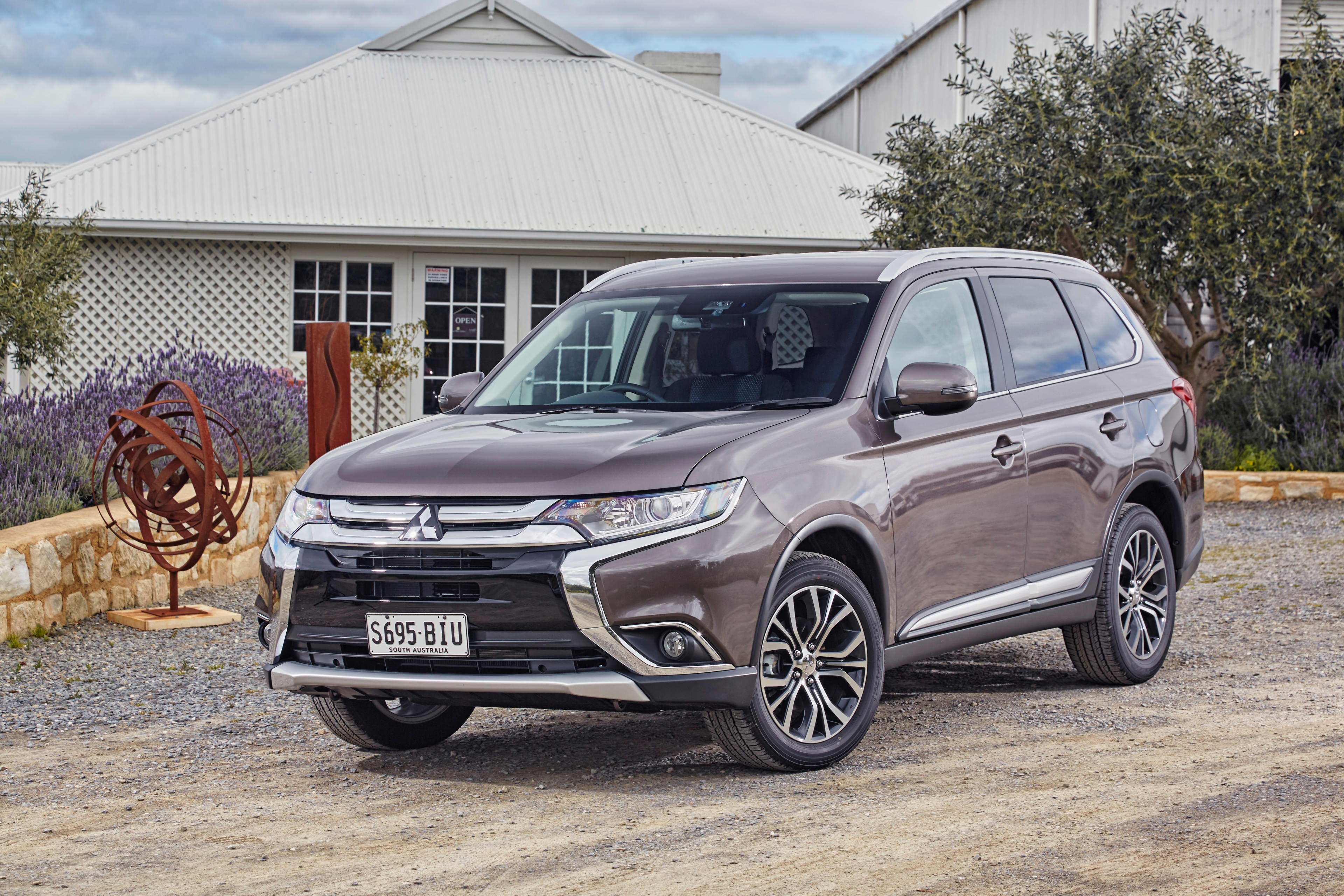 A grey Mitsubishi Outlander parked in front of a house.