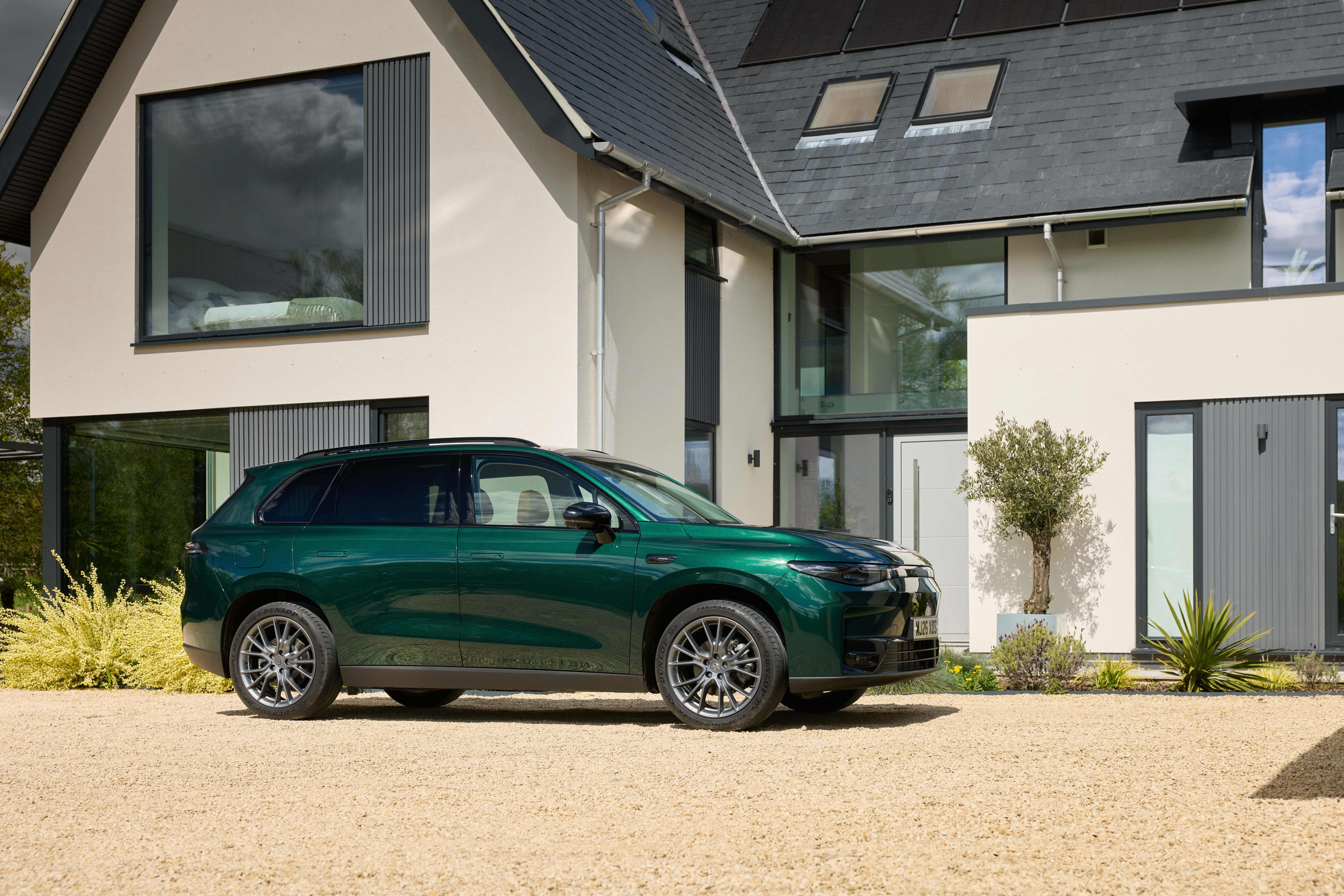 A dark green Leapmotor C10 REEV parked outside a home.