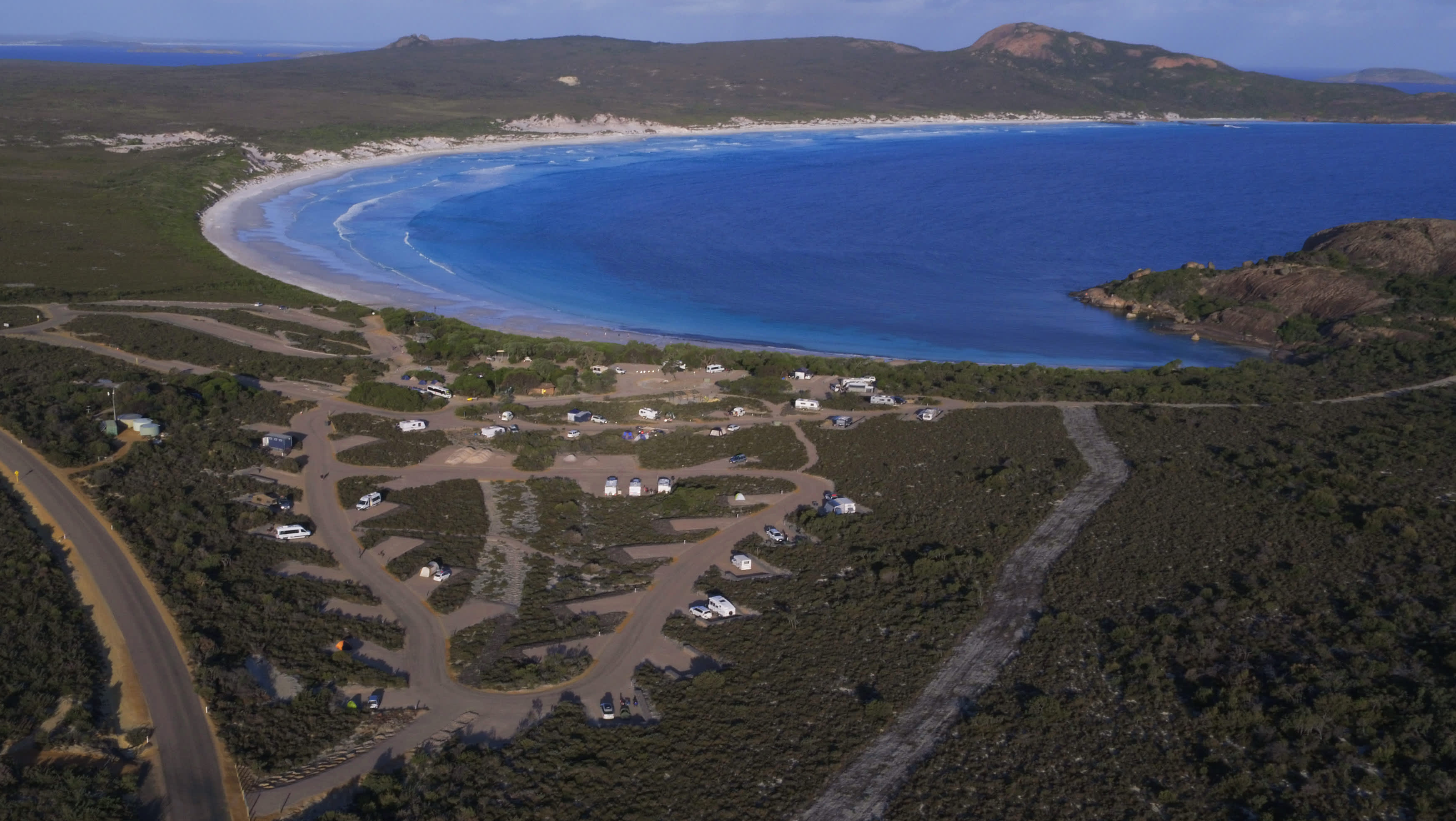 An aerial image showing the Lucky Bay campground roads and sites, nestled on the edge of the blue bay.