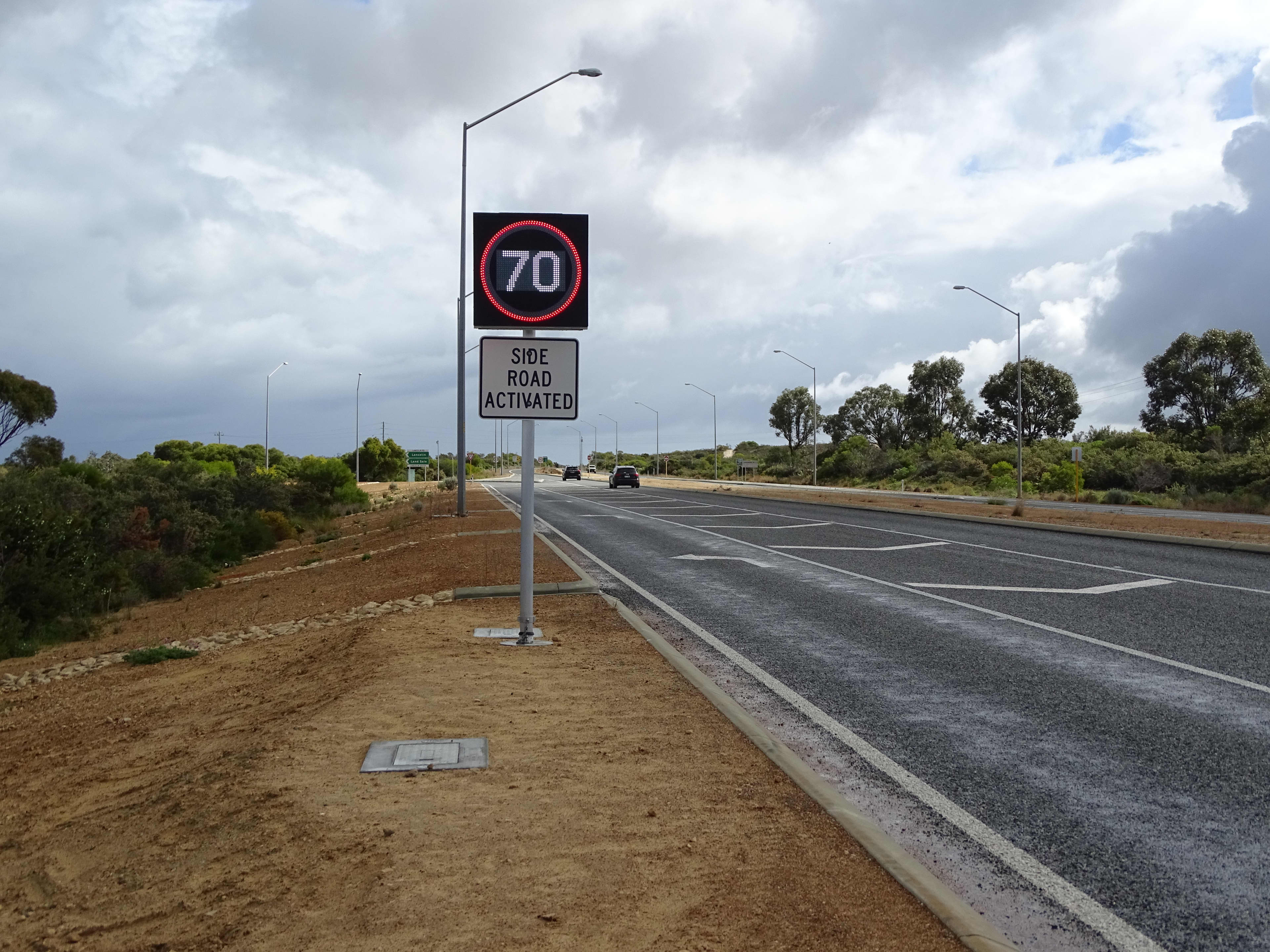 An electronic sign showing the speed 70kmh with the words 'side road activated' on a placard underneath, on the side of a WA highway.