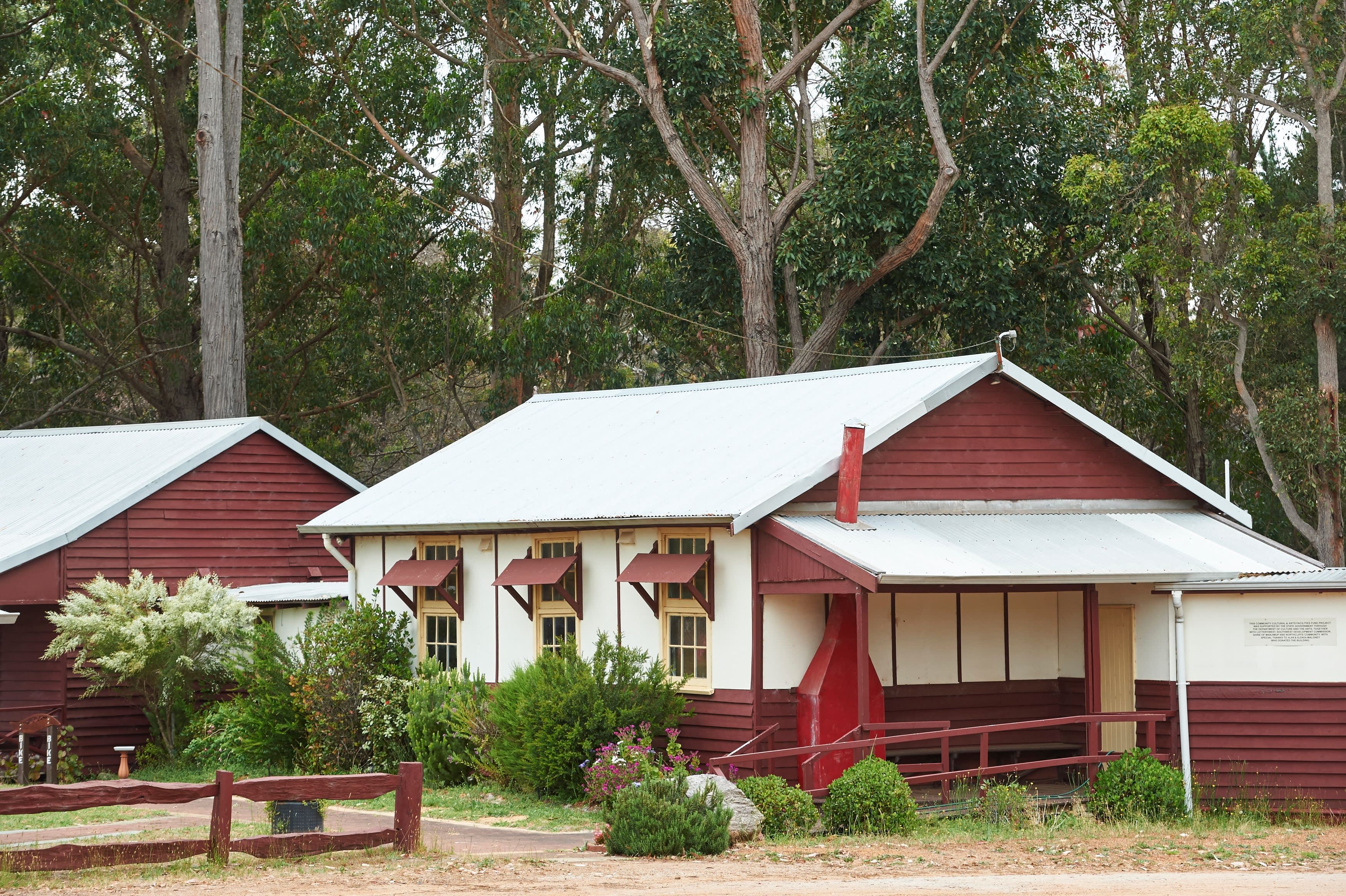 A cream-coloured heritage-style building nestled in lush, wooded setting.