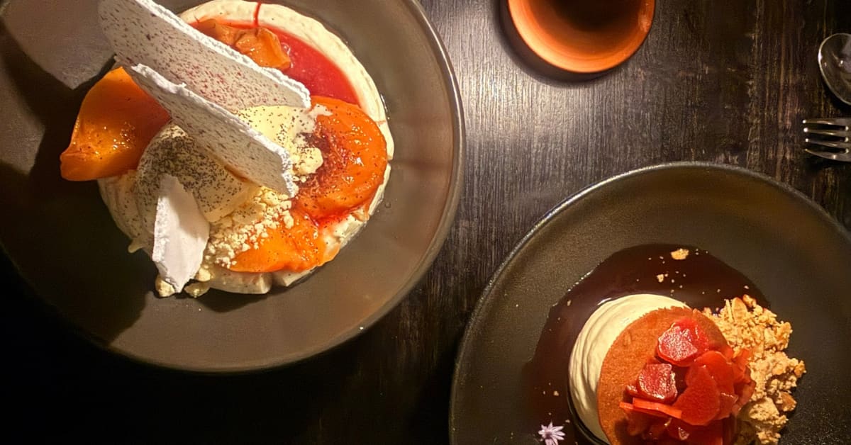 Two desserts on plates on black table