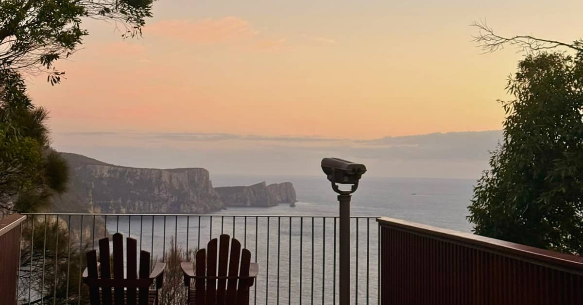Binoculars overlook sweeping coastal views from a lookout at sunset