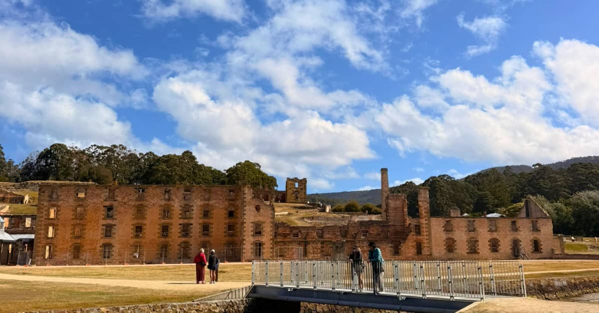 Tourists crossing bridge in front of large historic prison