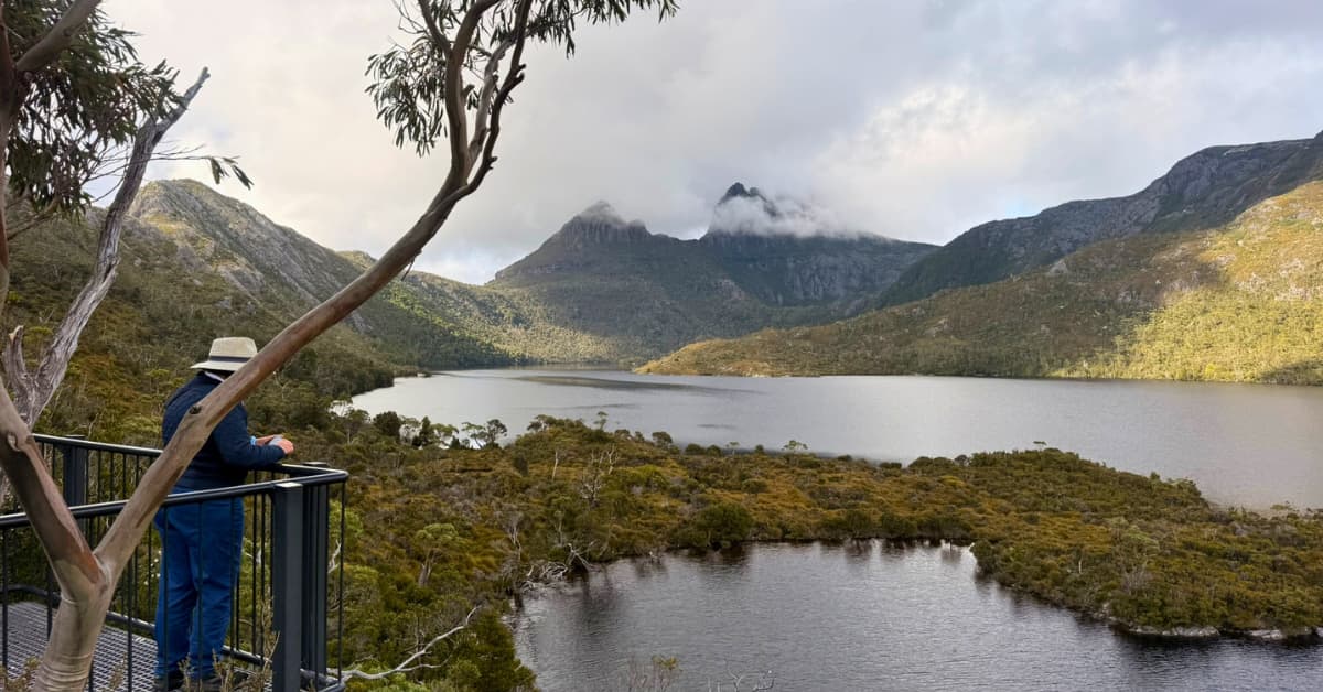 People standing on lookout overlooking large lake and mountains