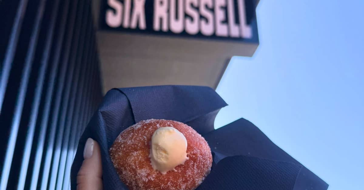 A lemon cream donut in a black napkin outside a shop sign