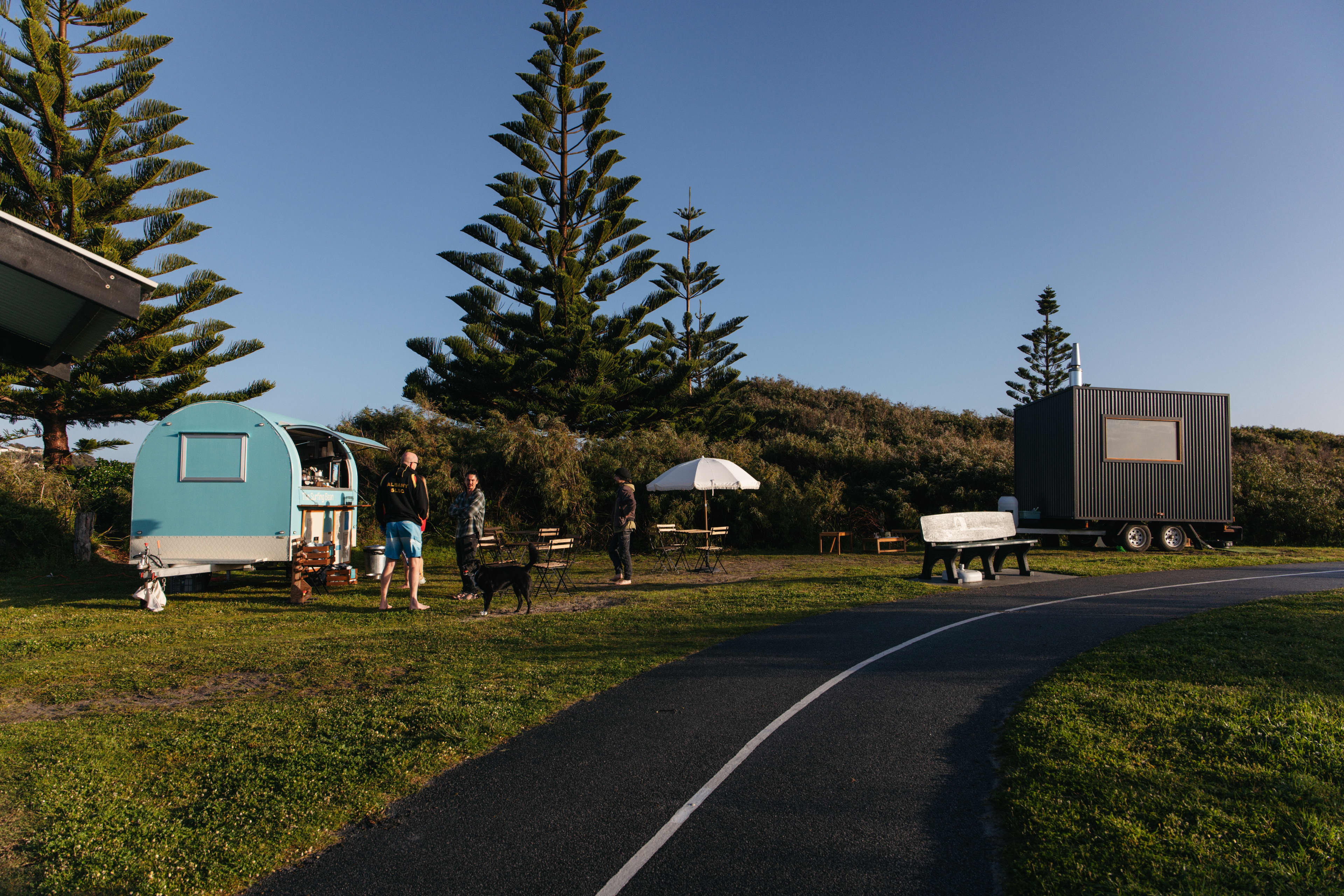 Mobile sauna van next to mobile coffee van alongside footpath and bushland