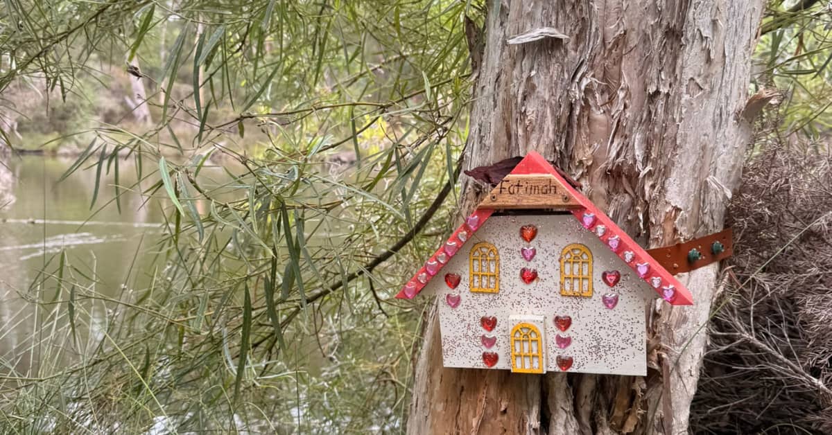 Tiny decorated fairy door on outside of tree by river