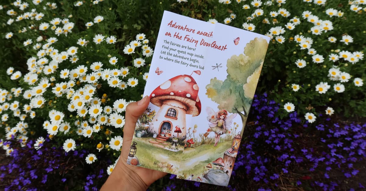 Hand holding fairy quest trail map with garden in background