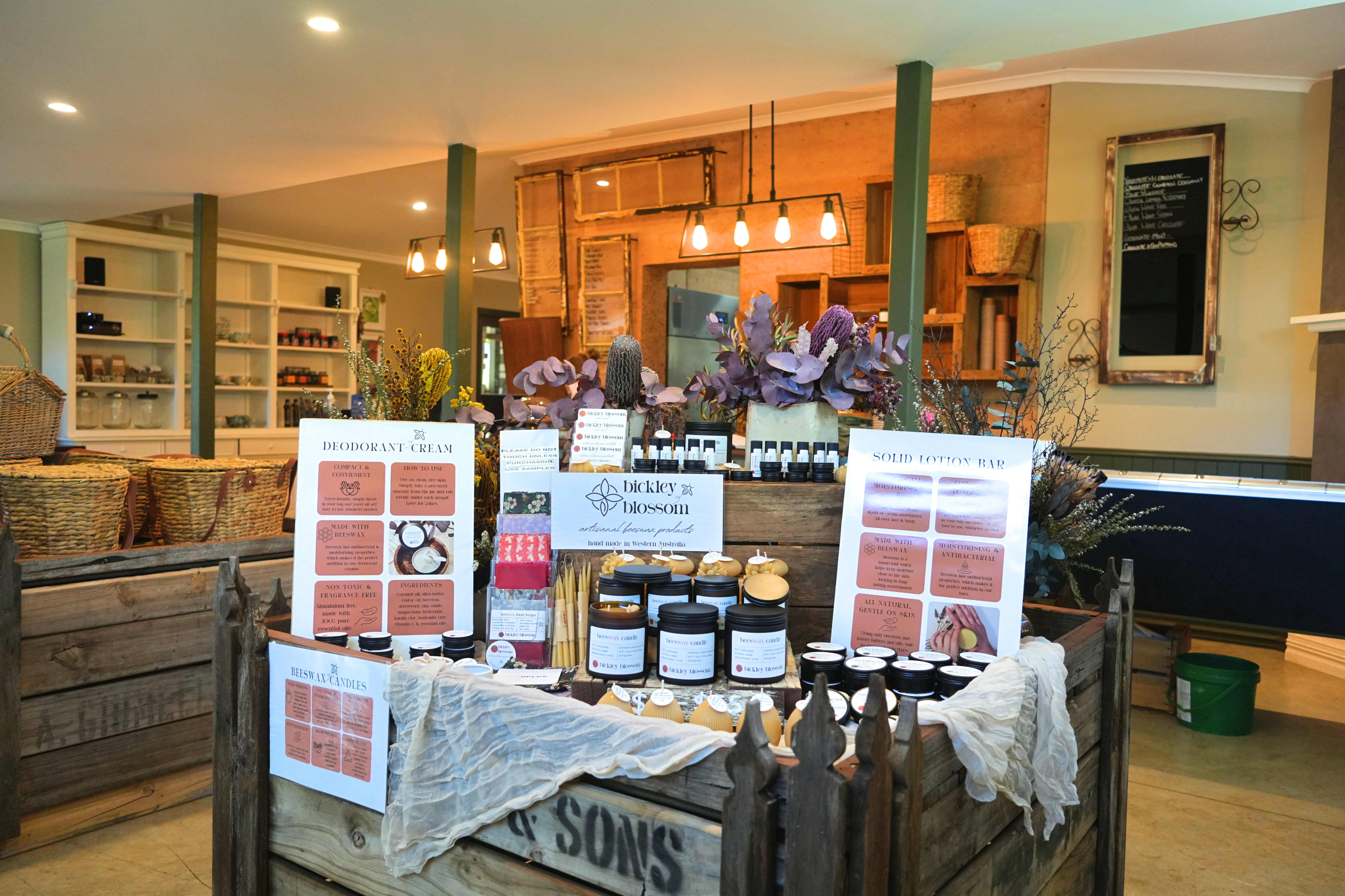 A warm lit room filled with wooden crates displaying local products with jars and baskets.