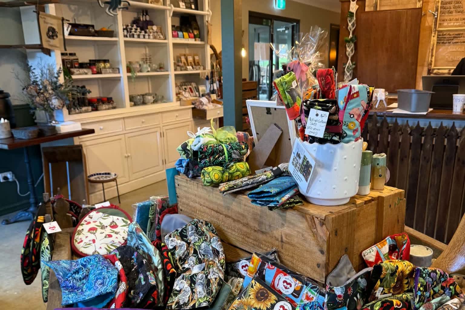 A rustic wooden crate used as a display table in the centre, filled with various colourful, patterned fabric items like small bags, pouches and wrapped gifts.