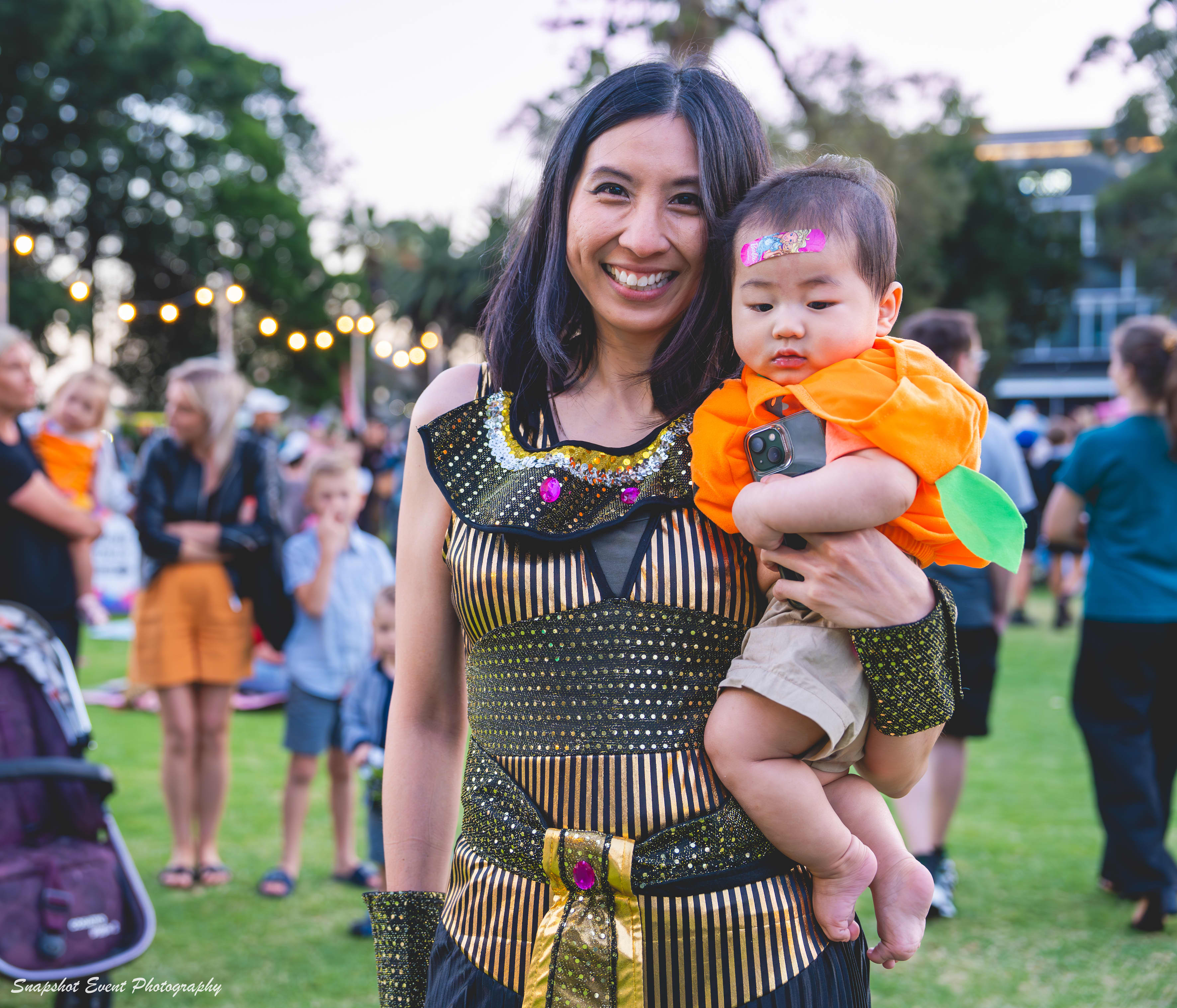 Woman and baby in costume at market event.