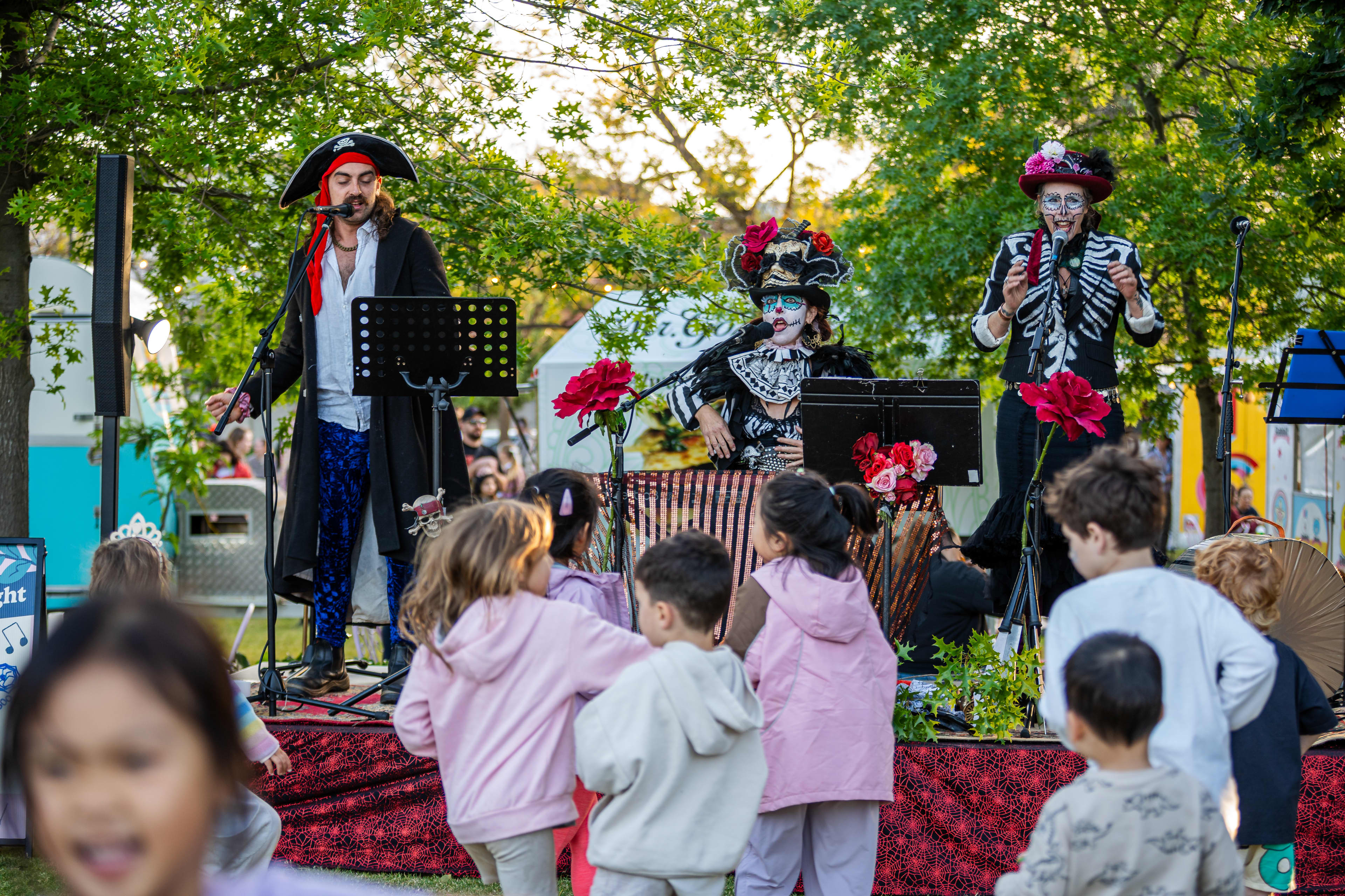 Children dancing in front of stage with musicians dressed in spooky costumes.