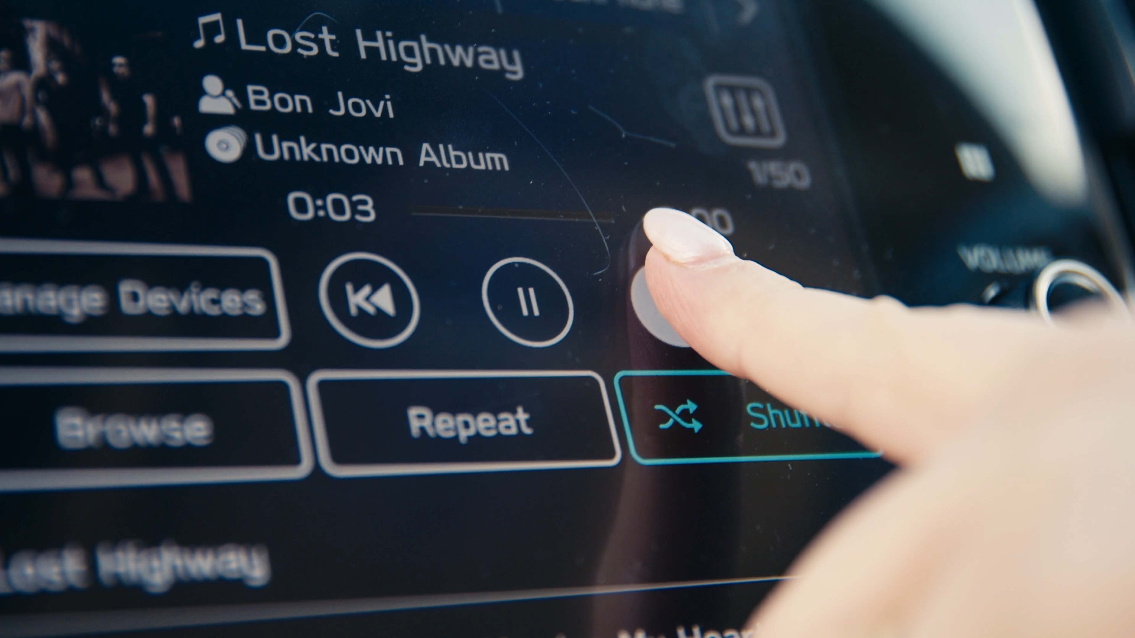 A close-up of a person pressing the fast forward button a song on the interactive screen on their car's dashboard.