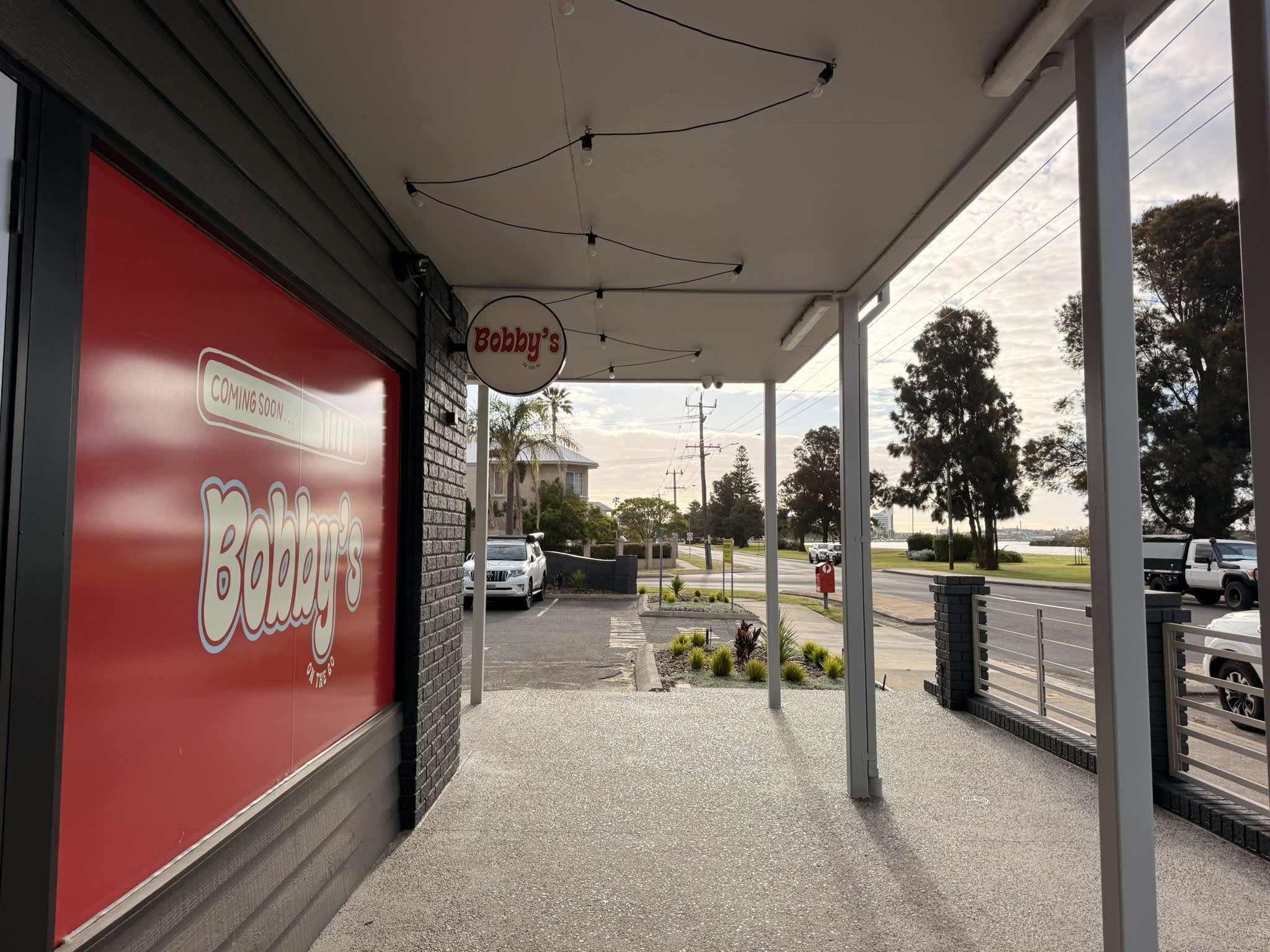 Waterfront cafe under development with Bobbys signage and red window poster.