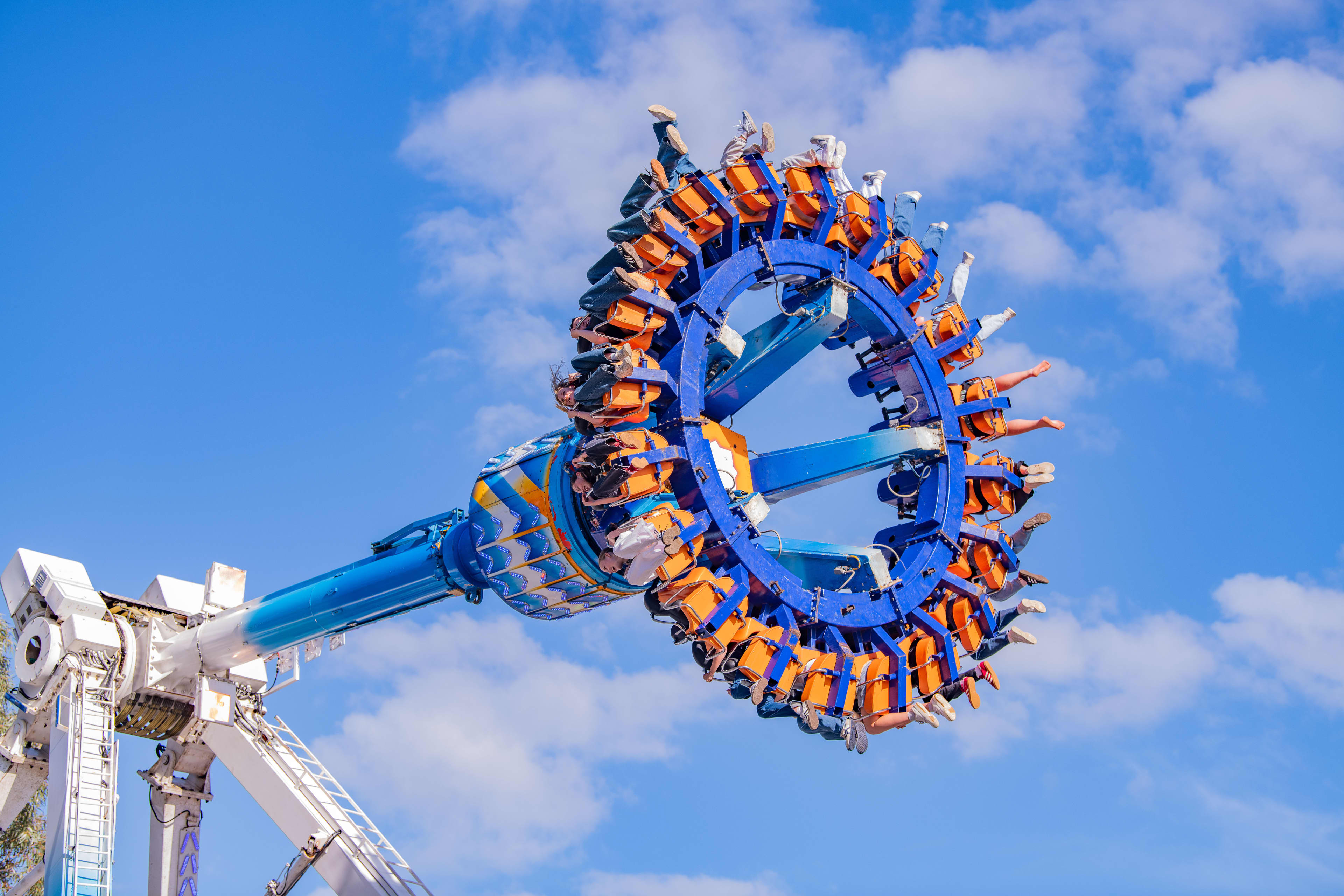 A circular blue ride with showgoers suspended in the air with bright blue skies in the background.