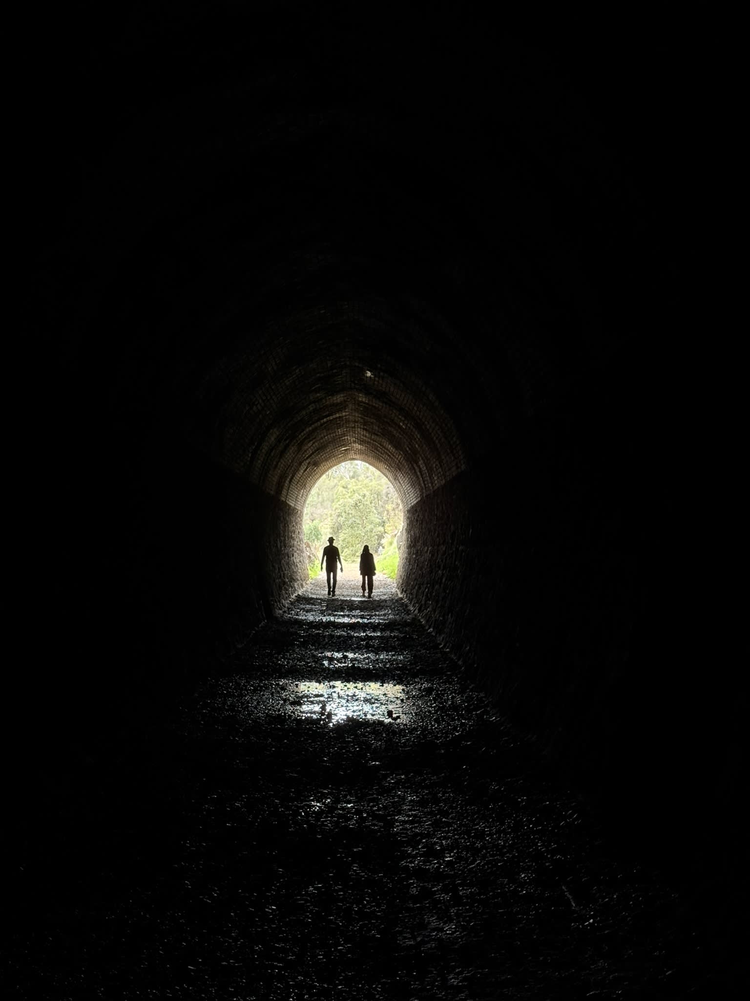 Dark tunnel with two silhouettes visible in distance