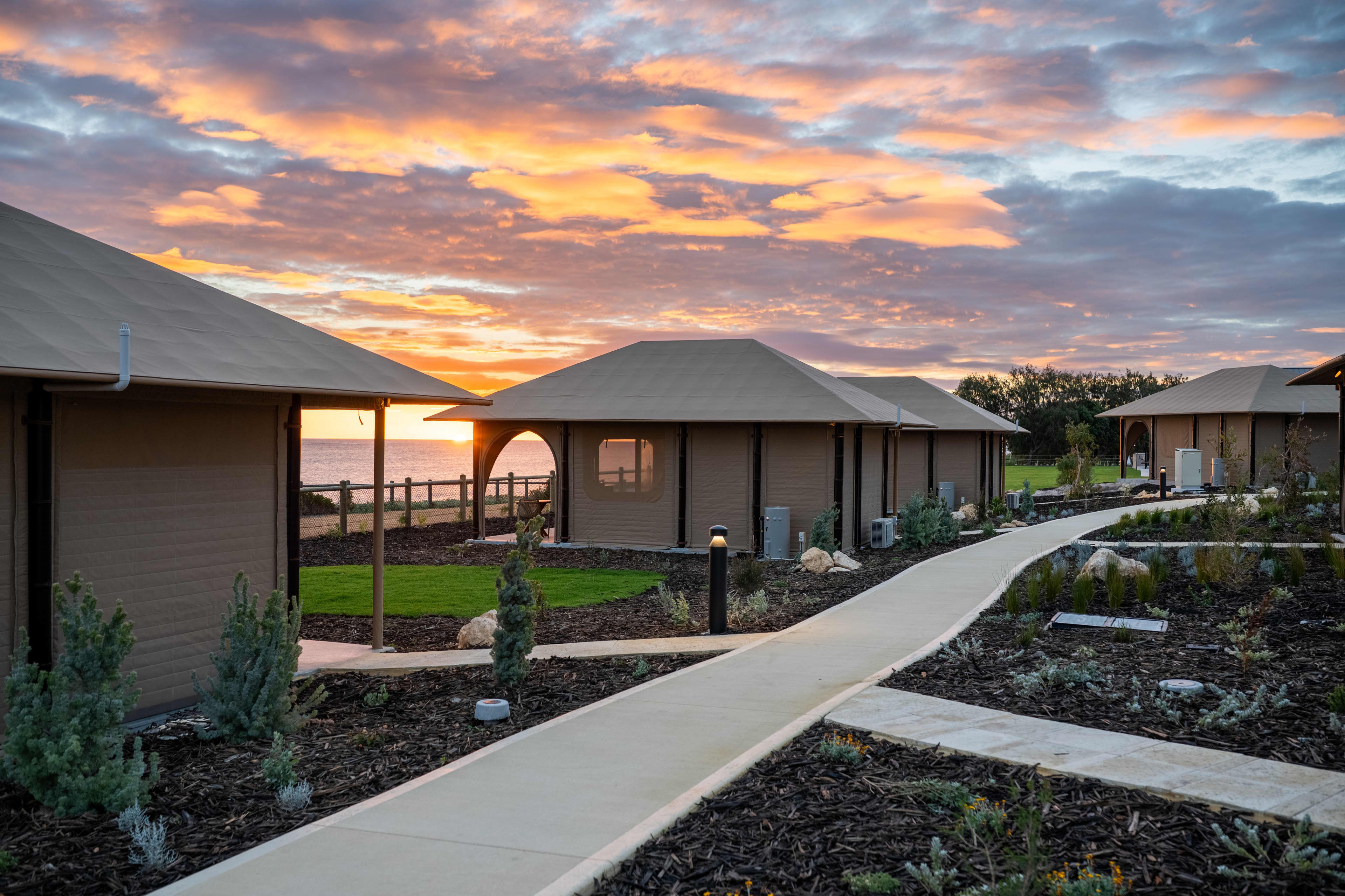 An exterior shot of a modern property at sunset features a series of geometric structures with triangular awnings and tents.