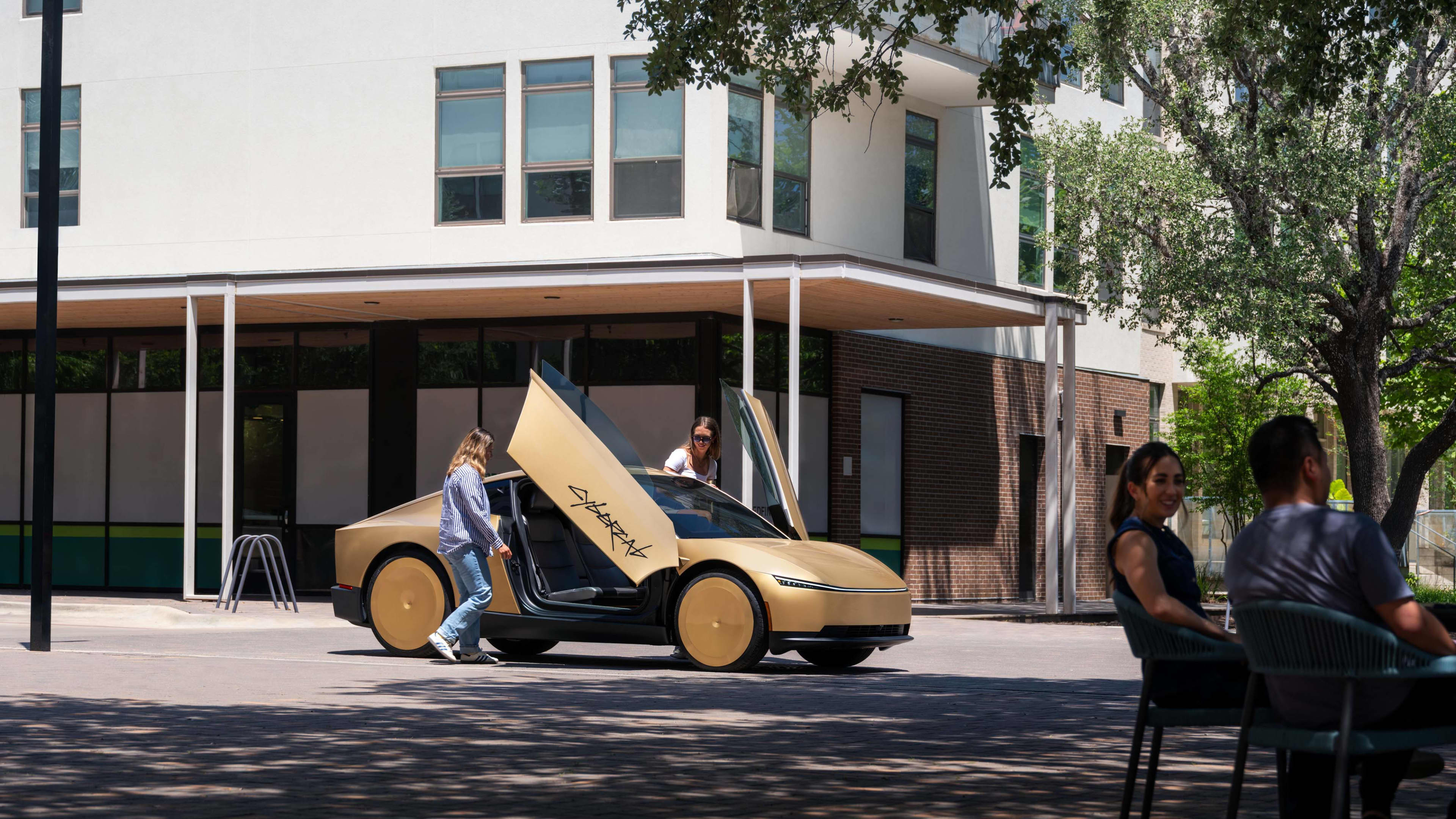 Two passengers about to get into a gold Cybercab outside a cafe.