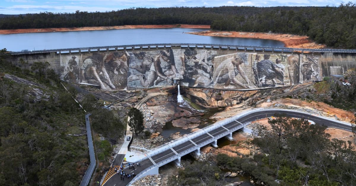 Aerial view of new pedestrian and traffic bridge underneath dam wall and mega mural.