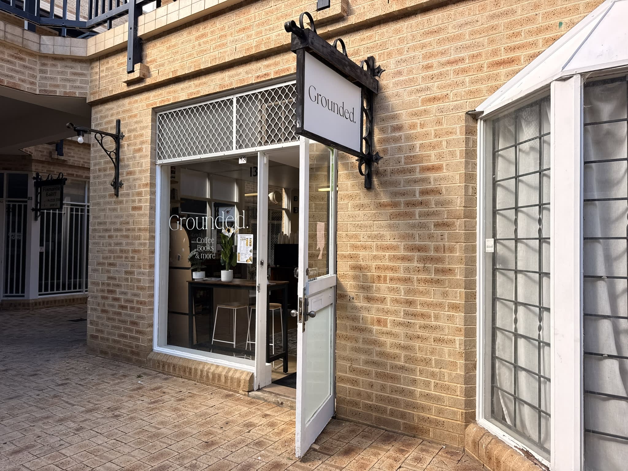 Brick building with cafe sign Grounded out the front.